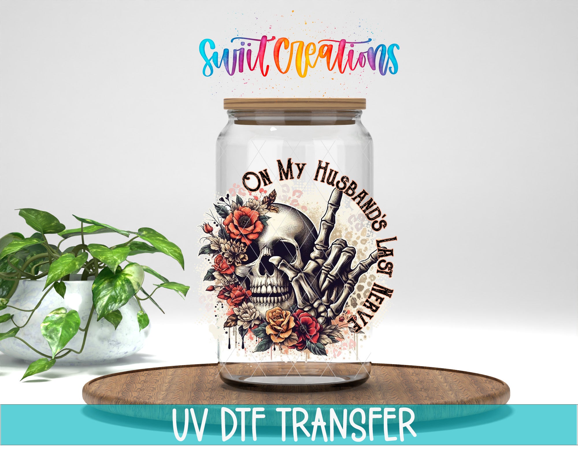a glass jar with a skull design and floral elements, placed on a wooden surface.