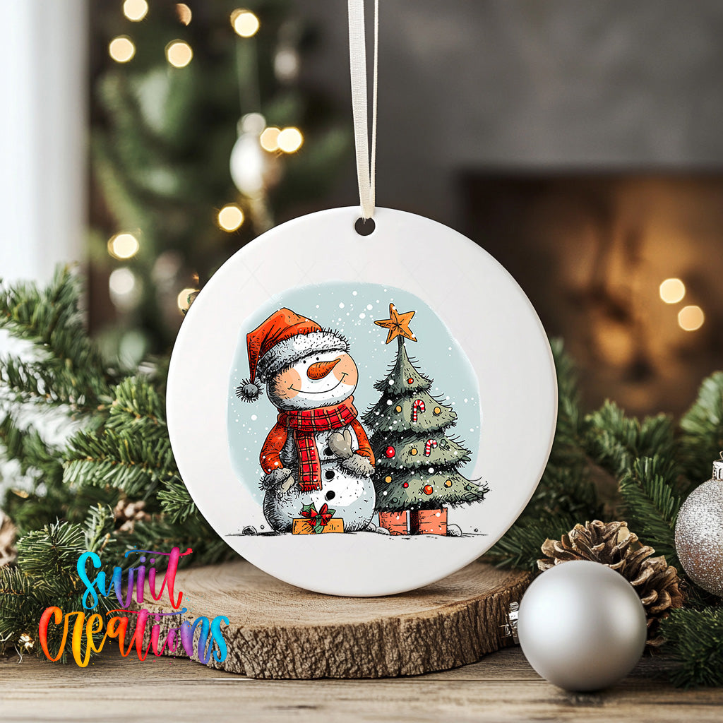 A white ceramic ornament featuring a snowman and a Christmas tree, surrounded by holiday decorations such as ornaments and pine cones.