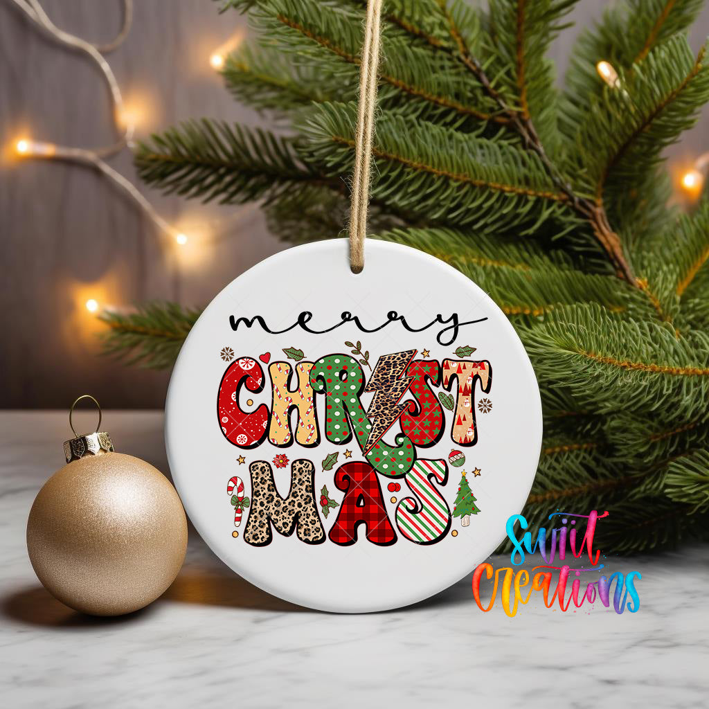 A white Christmas ornament with the text "Merry Christmas" written on it, hanging from a string. The ornament is placed next to a gold ornament and a pine tree, creating a festive holiday scene.