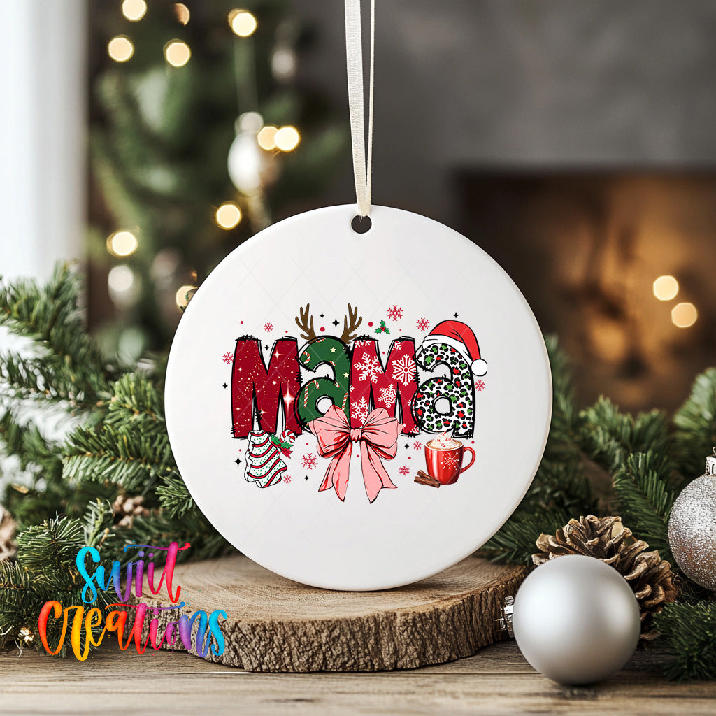 A white ceramic ornament with the word "Mama" written on it, surrounded by Christmas decorations such as pine branches, ornaments, and a mug.