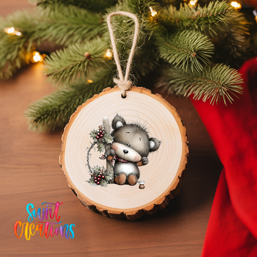 A wooden ornament featuring a cute cartoon cat is hanging on a Christmas tree, surrounded by pine branches and twinkling lights.