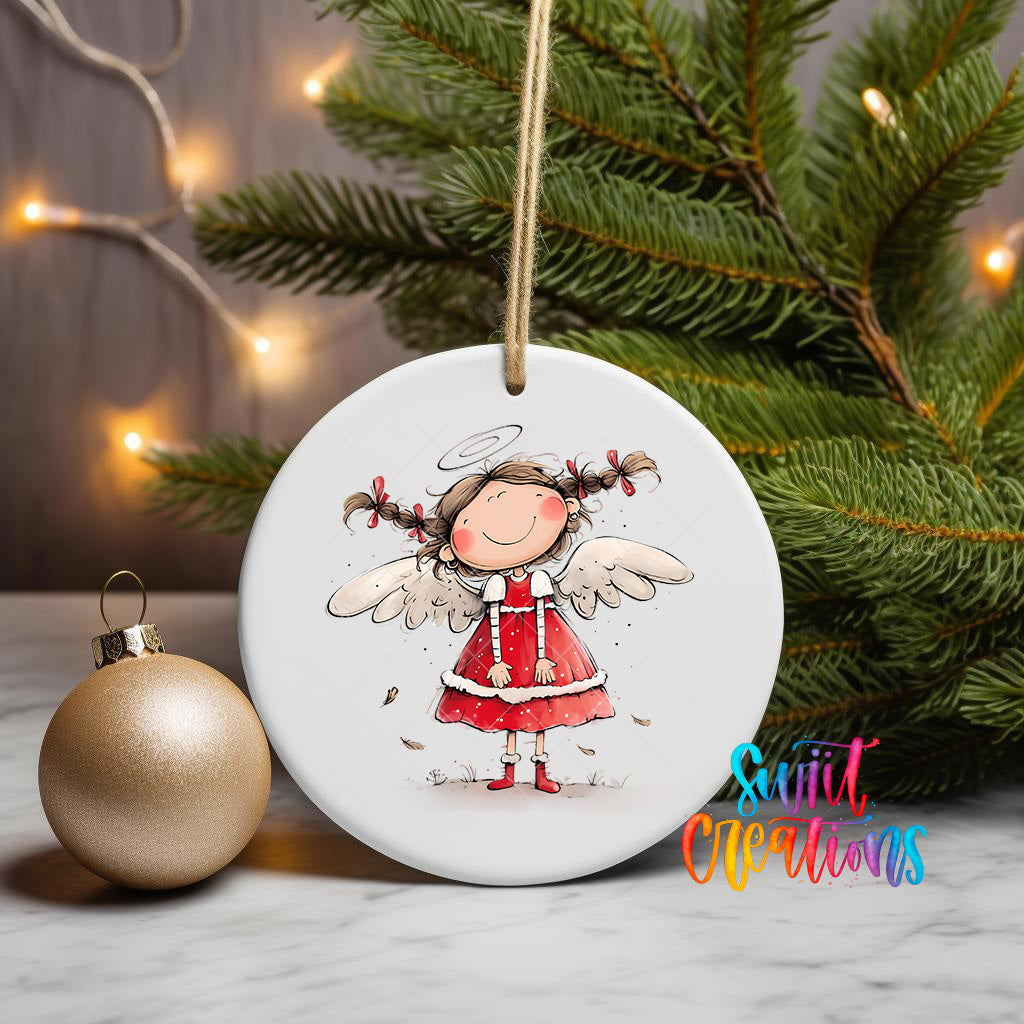 A white ceramic ornament featuring a smiling girl with angel wings, surrounded by Christmas lights and a pine tree.