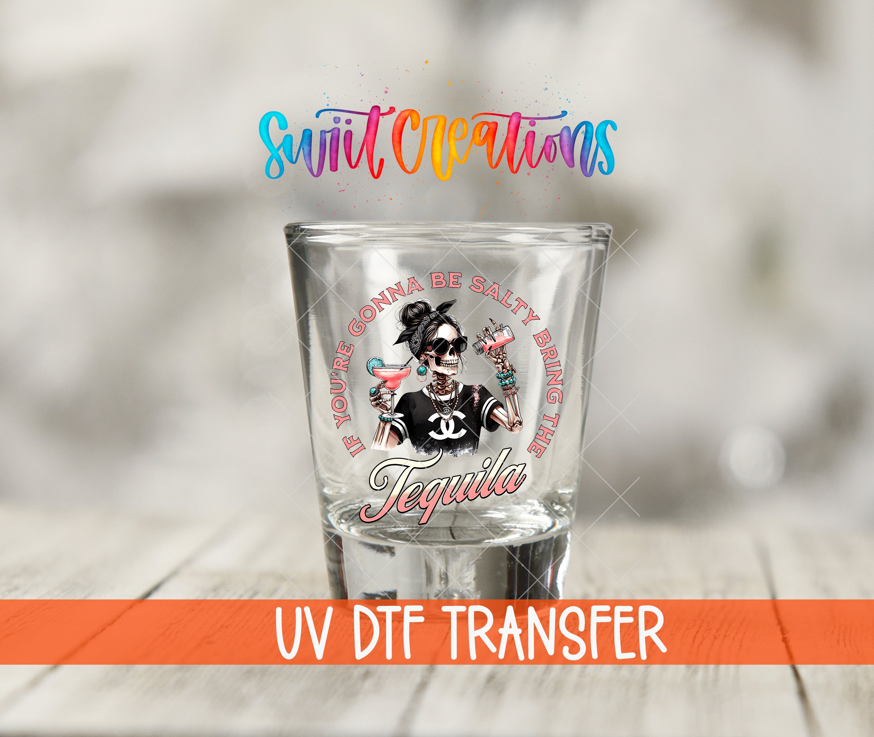 A shot glass with a colorful design and text, placed on a wooden surface.