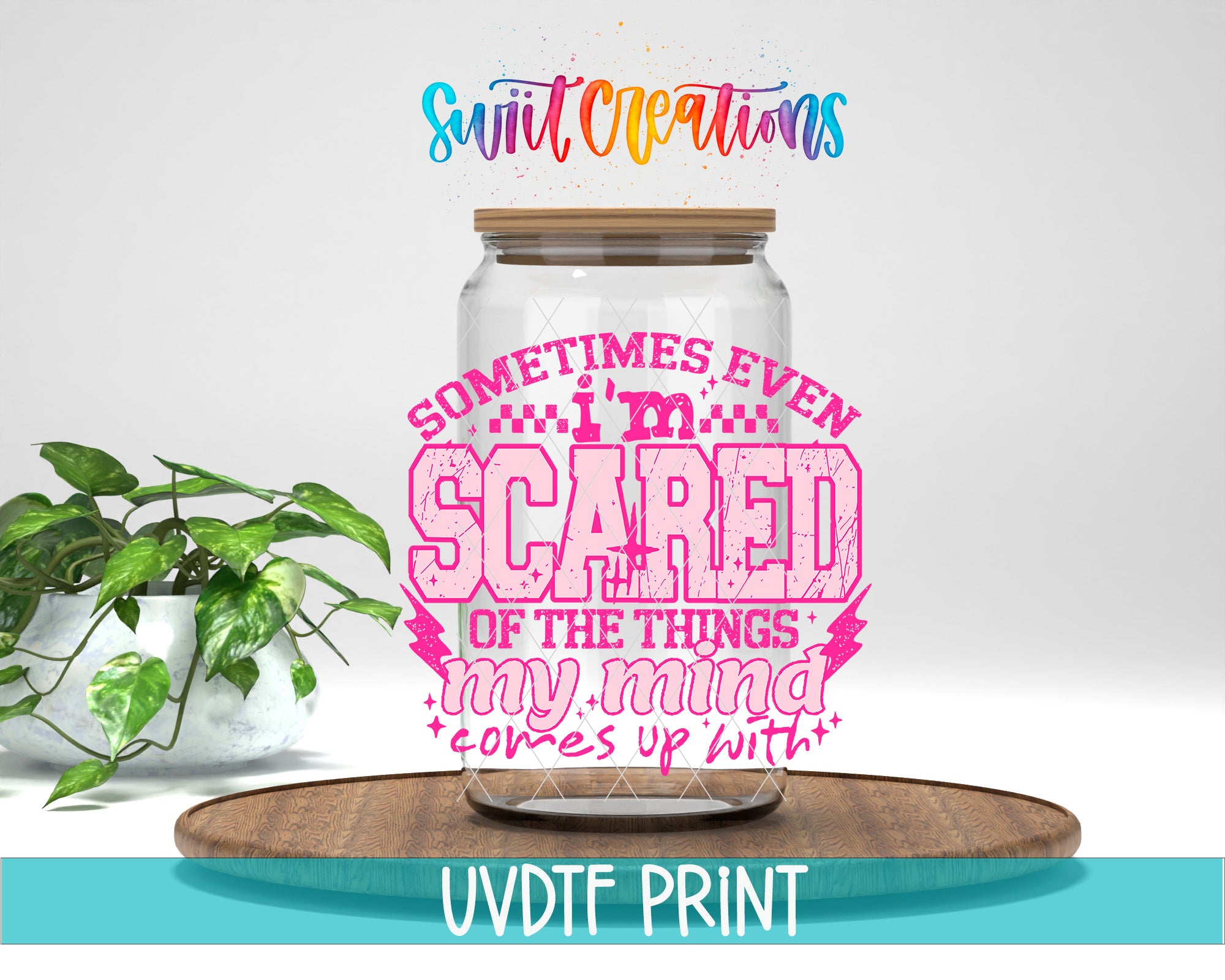 a large glass jar with a wooden lid, placed on a wooden surface. The jar has a colorful design with text and graphics on it. In the background, there is a potted plant. The image also includes text that reads "Swatch Creations" and "Sometimes even scared of the things my mind comes up with", along with the text "UVDF PRINT".