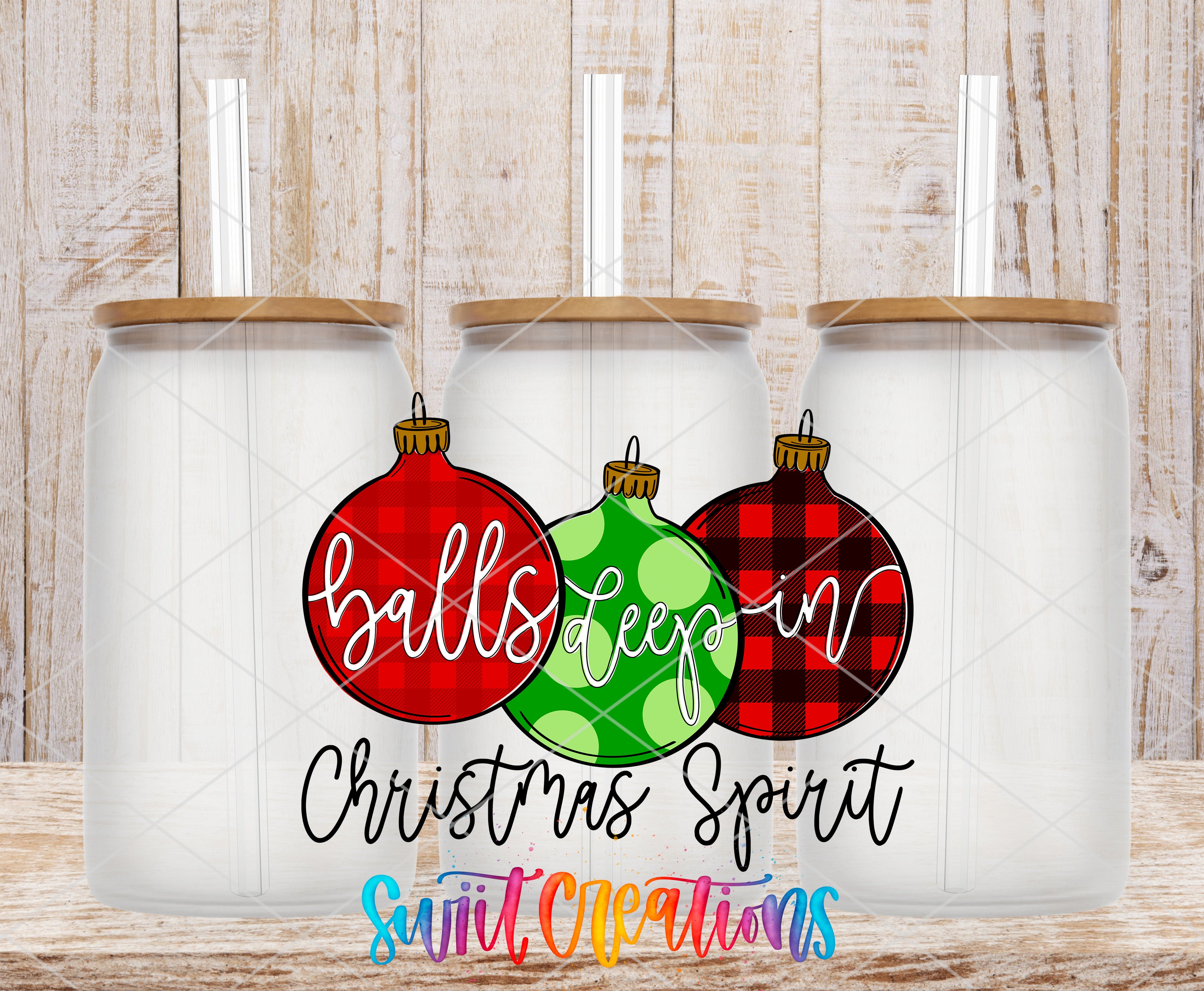 three glass jars with Christmas ornaments on them, arranged in a row against a wooden background.