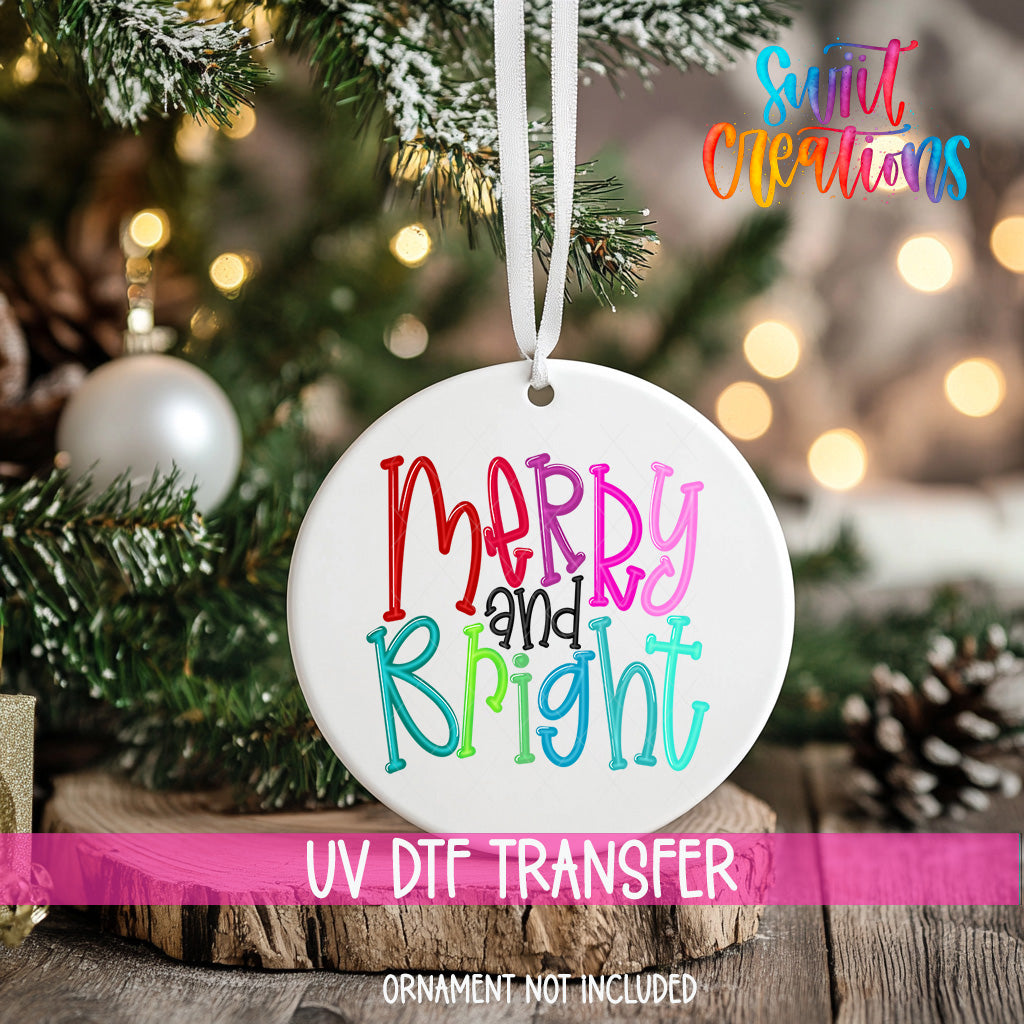A white ceramic ornament with the text "Merry and Bright" in colorful letters hangs from a Christmas tree.