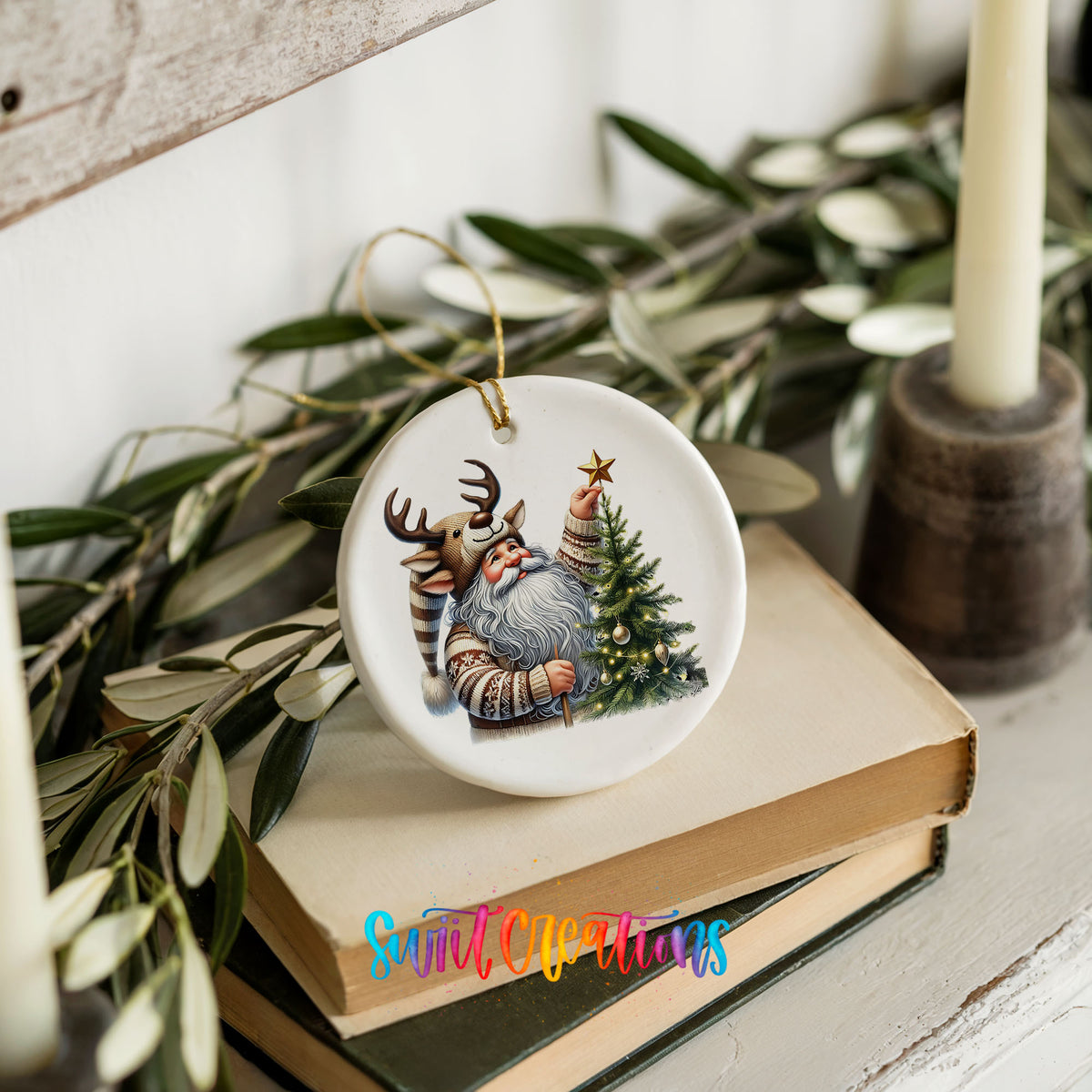 Round ceramic Christmas ornament featuring Santa placing a star on a Christmas tree, styled on books with holiday greenery