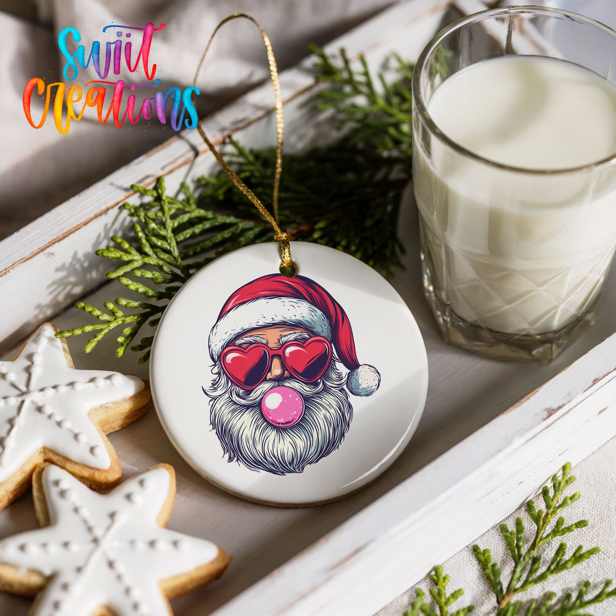 Round ceramic Christmas ornament featuring retro Santa wearing sunglasses and blowing pink bubblegum, styled with cookies and milk
