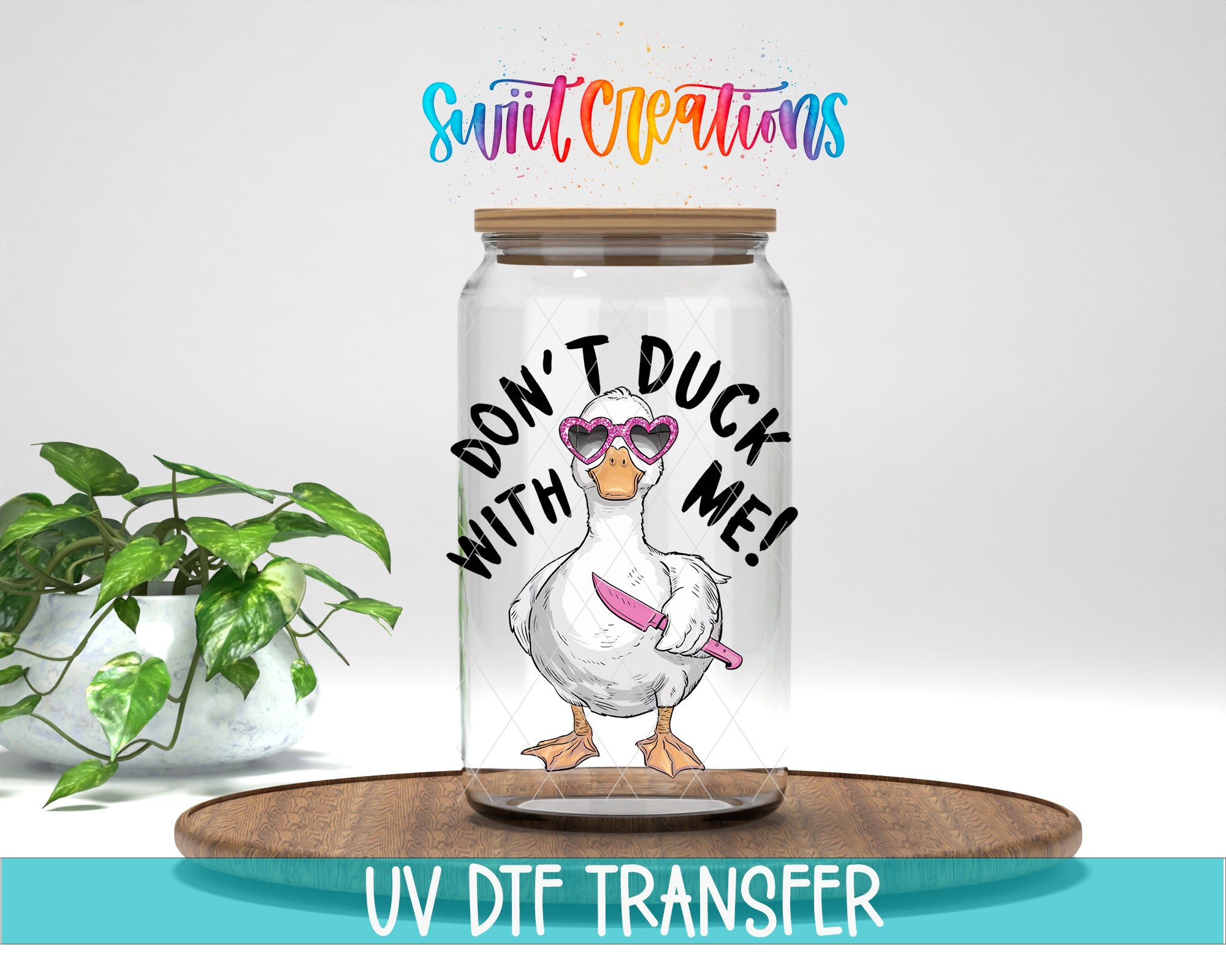 a glass jar with a cartoon duck wearing sunglasses and holding a knife, accompanied by the text "DON'T DUCK WITH ME!" The jar is placed on a wooden surface, and there is a potted plant in the background.