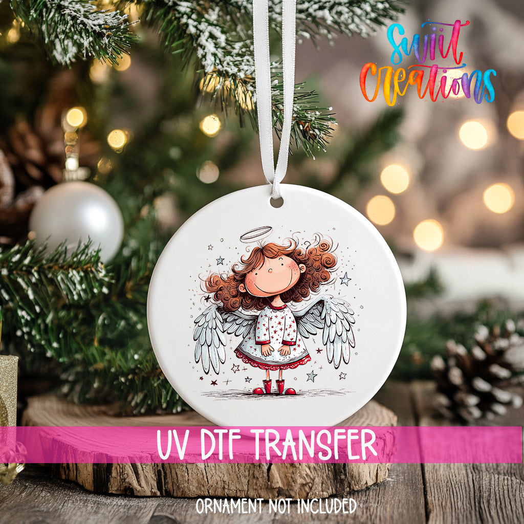 A white ceramic ornament with a smiling cartoon girl with curly hair and wings, hanging on a Christmas tree.