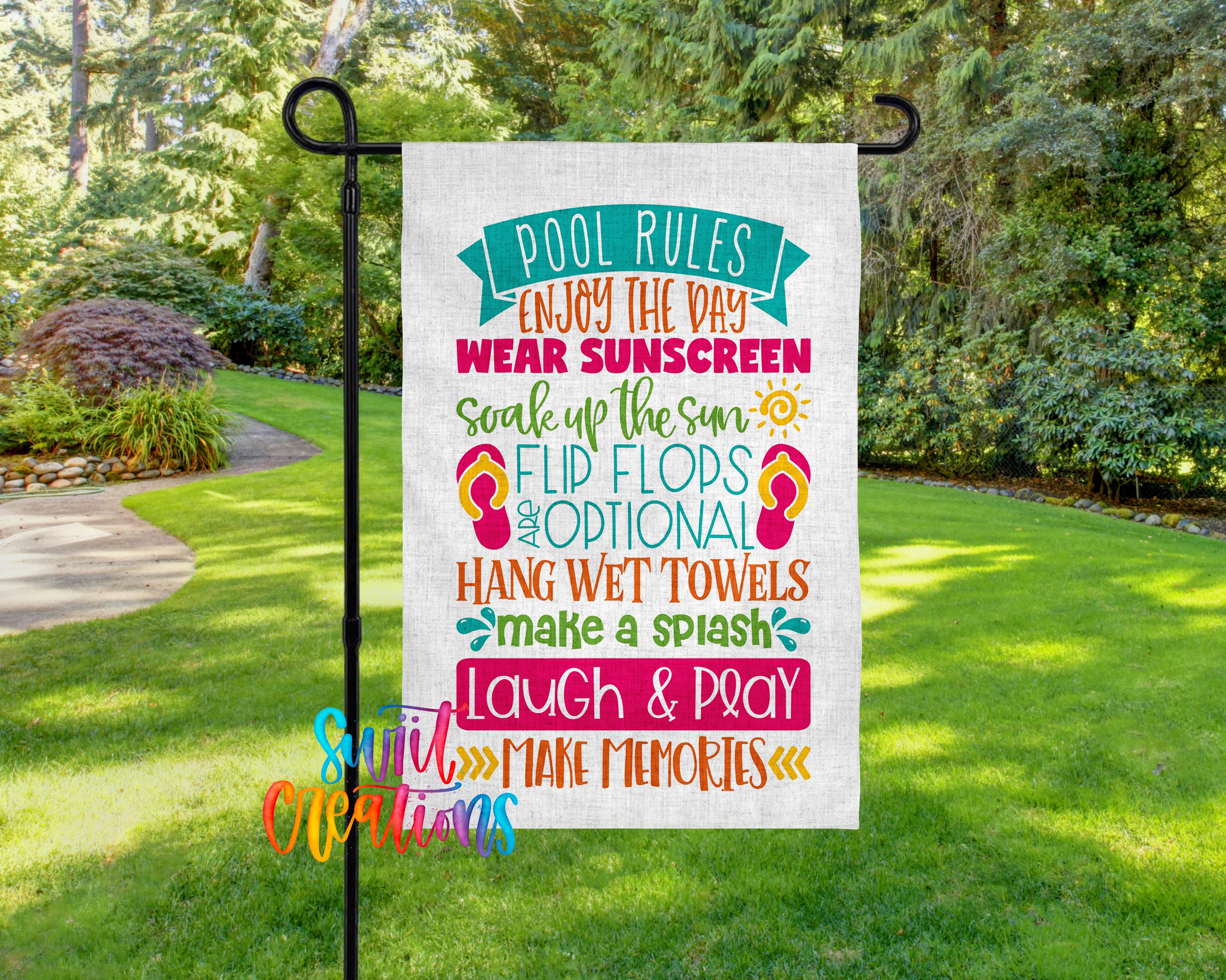 A colorful sign with text that reads "I pool rules enjoy the day wear sunscreen soak up the sun flip flops are optional hang wet towels make a splash laugh & pray" is displayed in a garden setting.