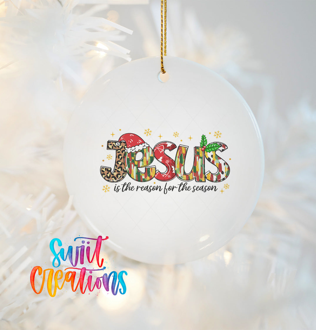 A white ornament with the word "JESUS" written in a colorful, stylized font, surrounded by decorative elements such as snowflakes and stars.