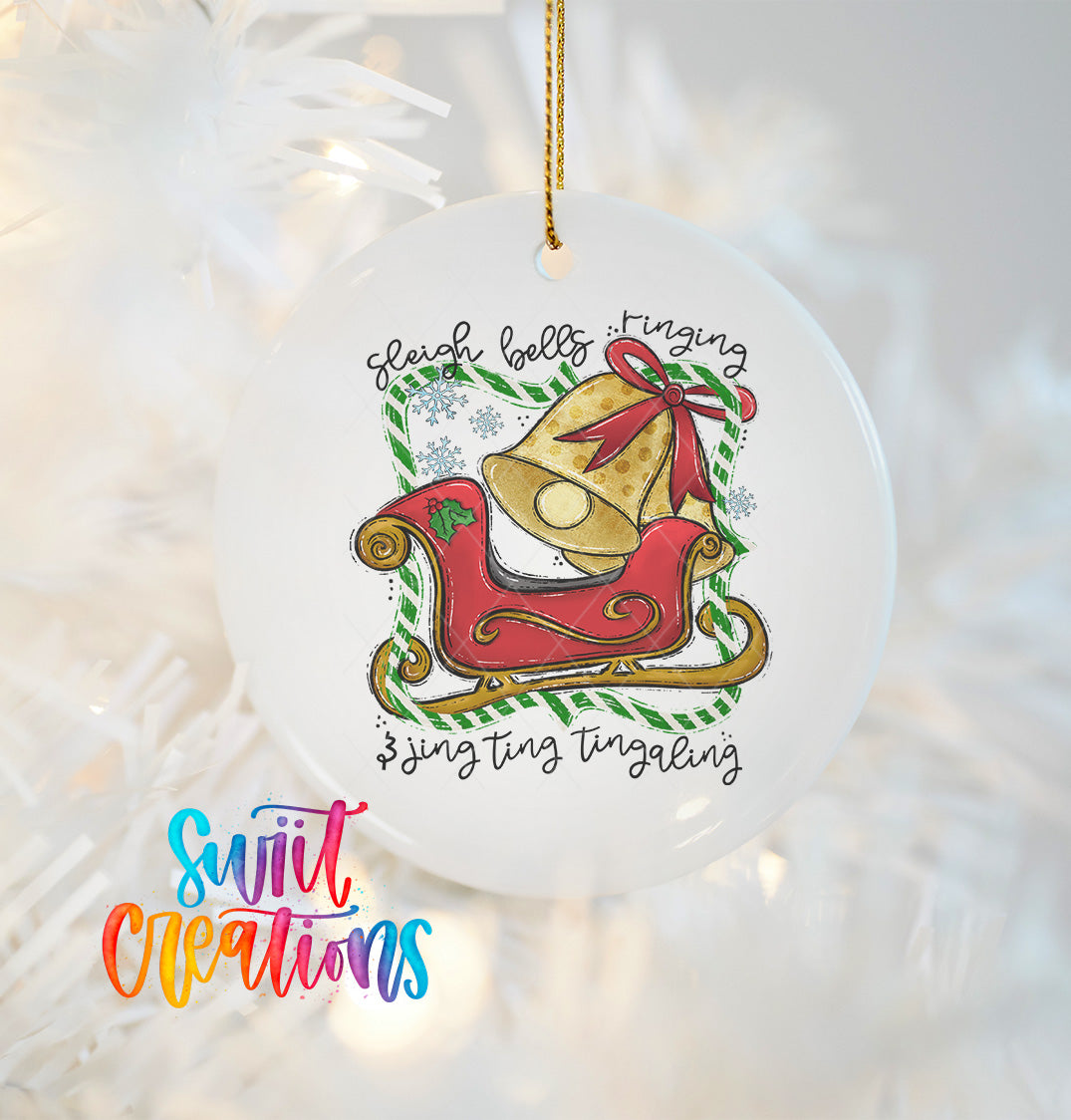 A white ornament with a red sleigh and a bell, hanging on a string.