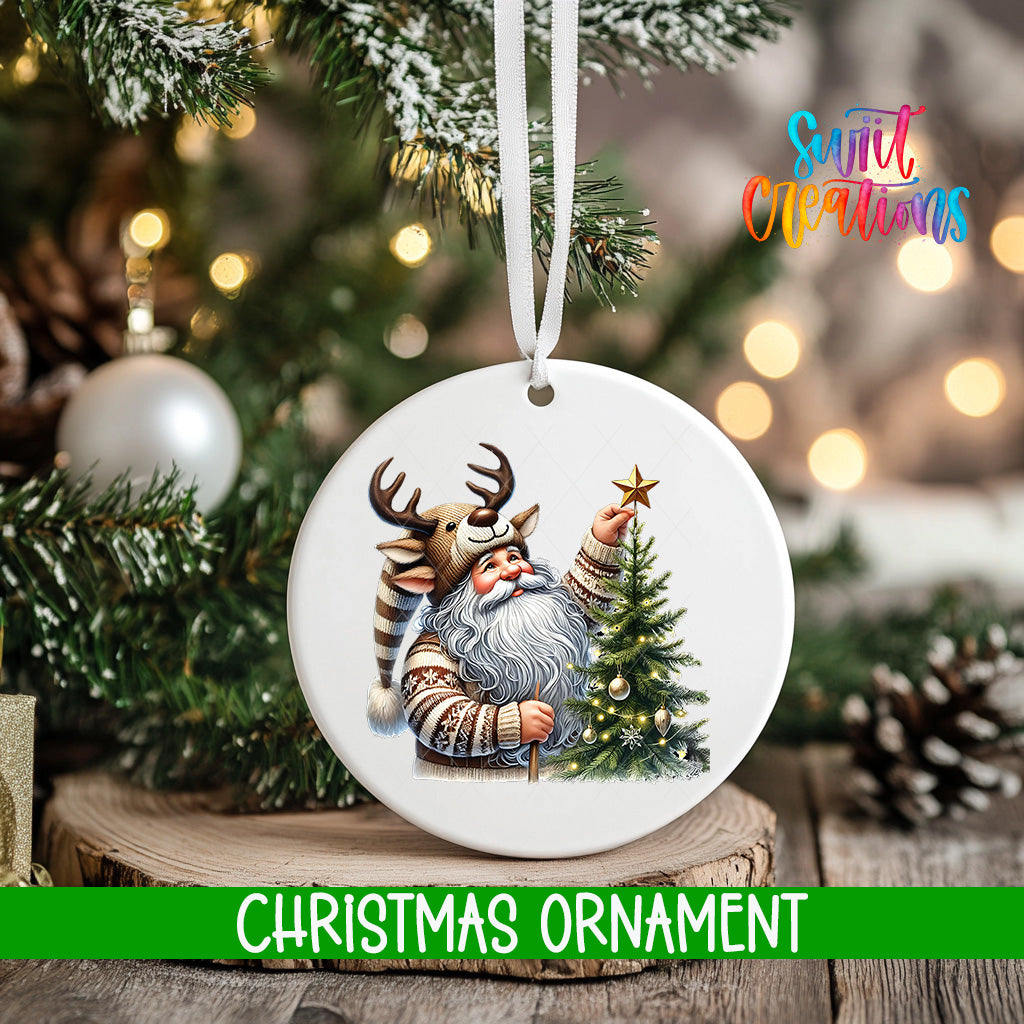 A white Christmas ornament featuring a Santa Claus figure holding a star, surrounded by a decorated Christmas tree and pine cones.