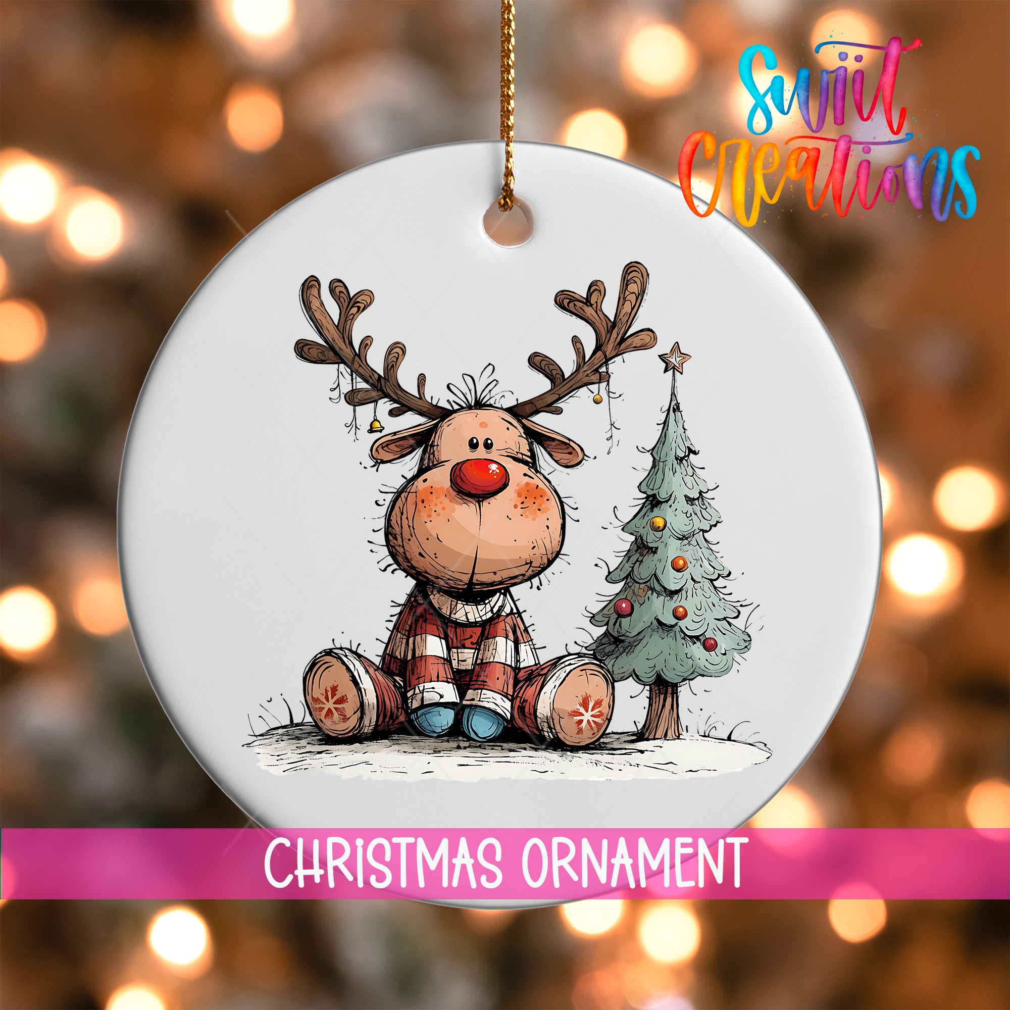 A white Christmas ornament featuring a cartoon reindeer sitting next to a Christmas tree.