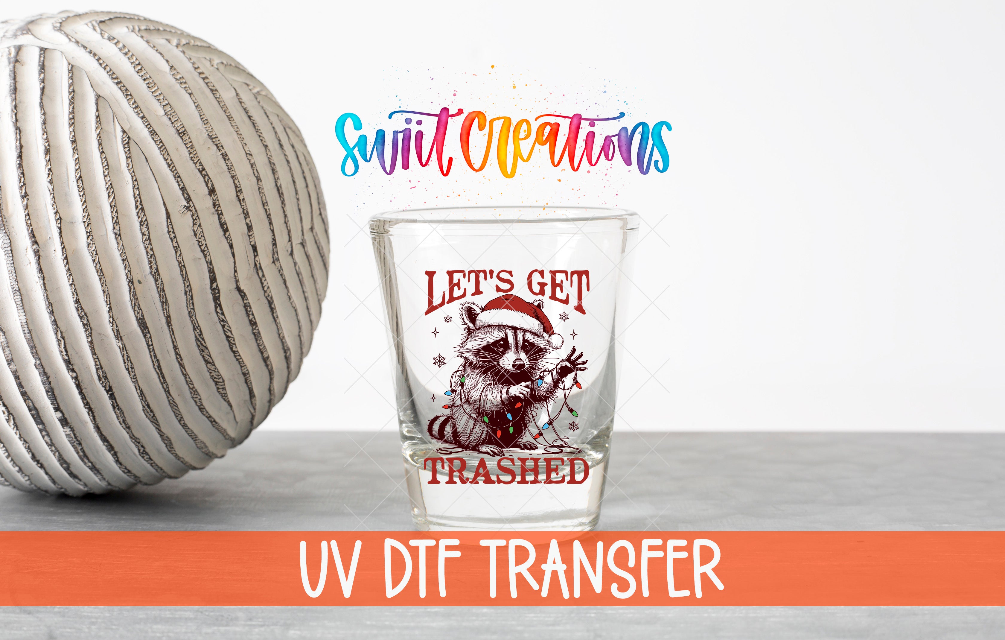 a glass with a raccoon wearing a Santa hat and the text "Let's get trampled" on it, along with a text overlay that says "Swit Creations UV Dtf Transfer".