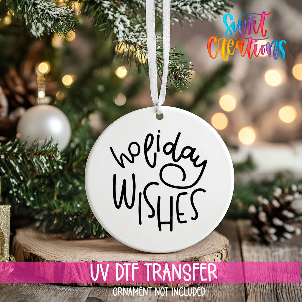 A white ornament with the text "Holiday Wishes" hanging on a Christmas tree, with a blurred background of lights and greenery.