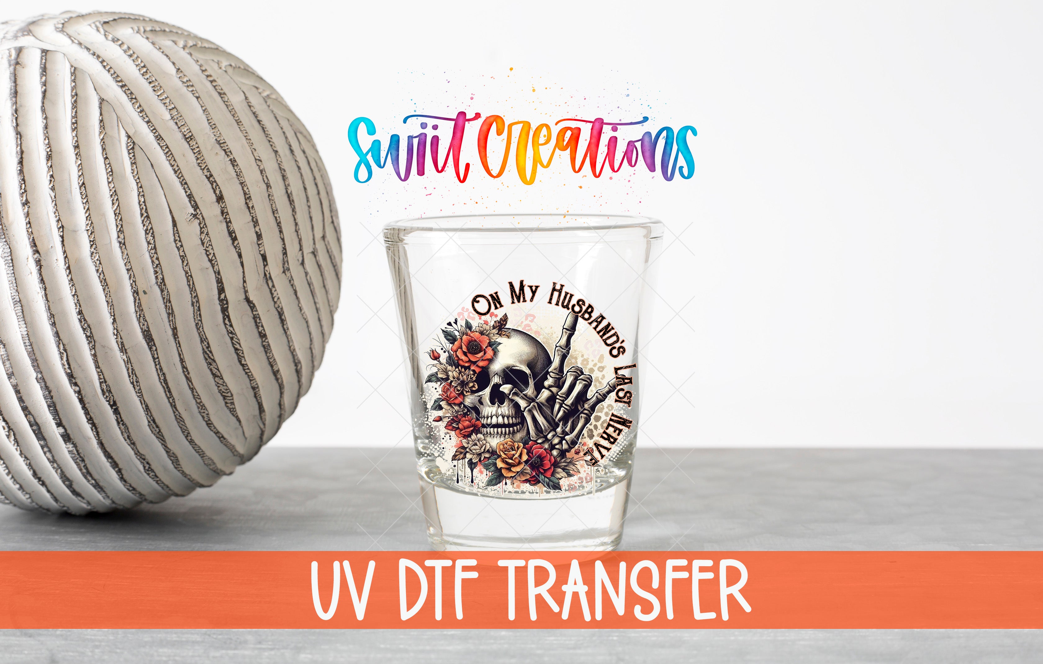 a glass with a skull design and floral elements, placed on a table next to a white ball. The text above the glass reads "Swift Creations" and "UV Dtf Transfer".