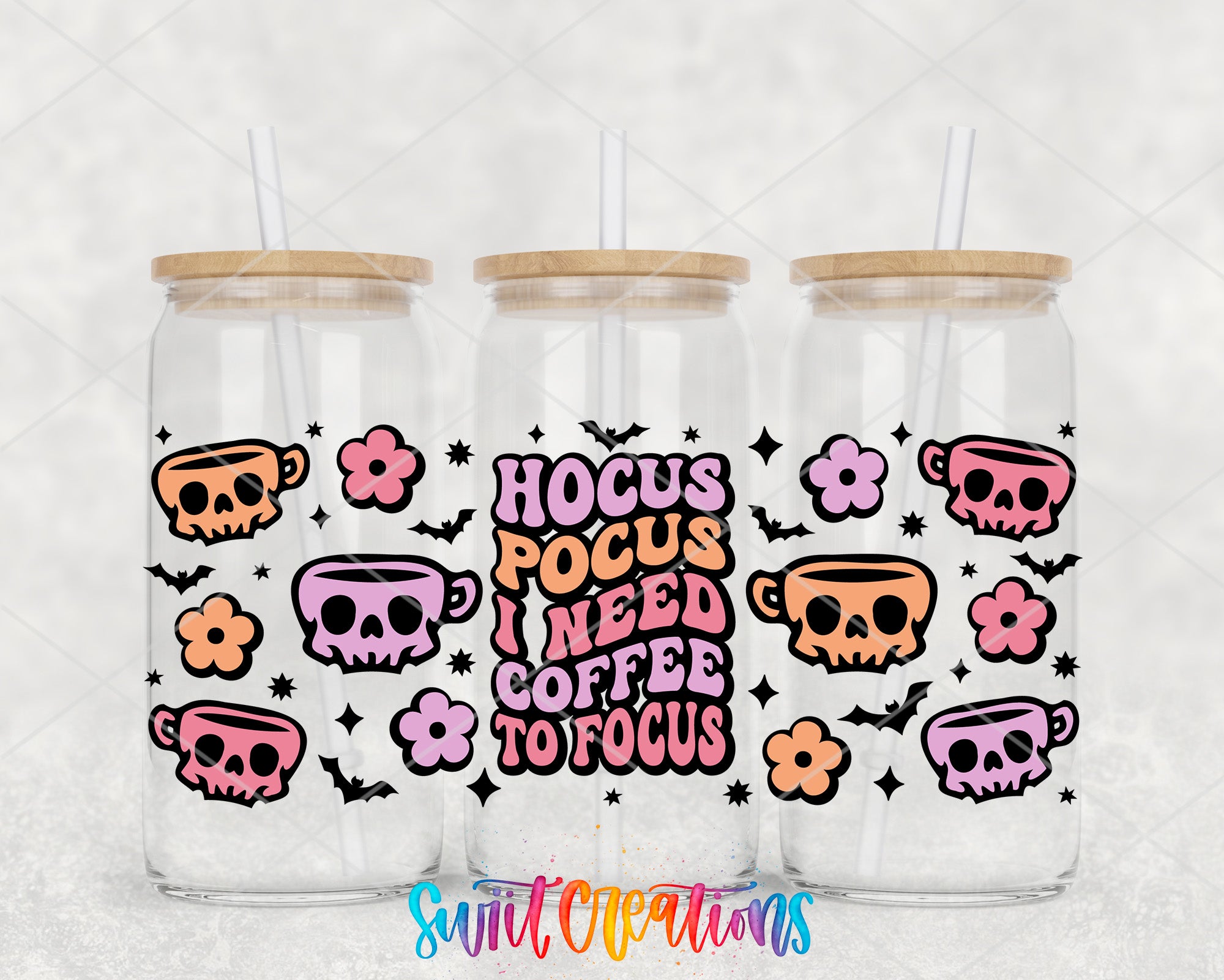 three clear glass tumblers with wooden lids, each adorned with a whimsical design and text. The design includes skull motifs, flowers, and stars, creating a playful and festive atmosphere. The text on the tumblers reads "HOCUS POCUS I NEED COFFEE TO FOCUS", which adds a humorous and quirky touch to the overall presentation.