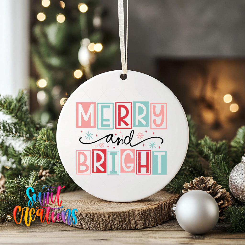 A white ceramic ornament with the text "MERRY AND BRIGHT" in a colorful, stylized font is displayed on a wooden surface, surrounded by Christmas decorations such as pine cones and ornaments.