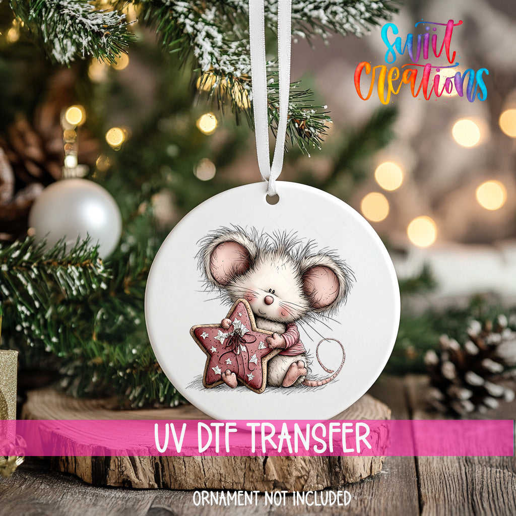 A white ceramic ornament with a mouse and star-shaped ornament is hanging on a Christmas tree.