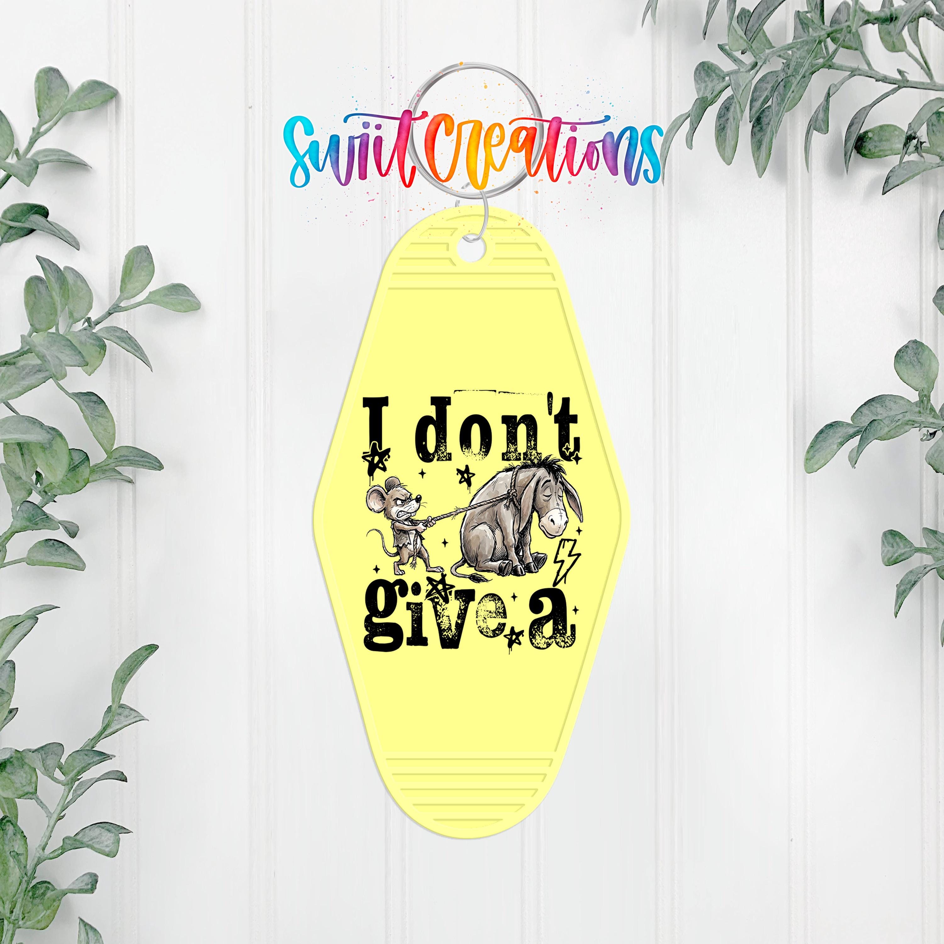 A yellow keychain with a cartoon image of Eeyore and the text "I don't give a" hanging on a wall.