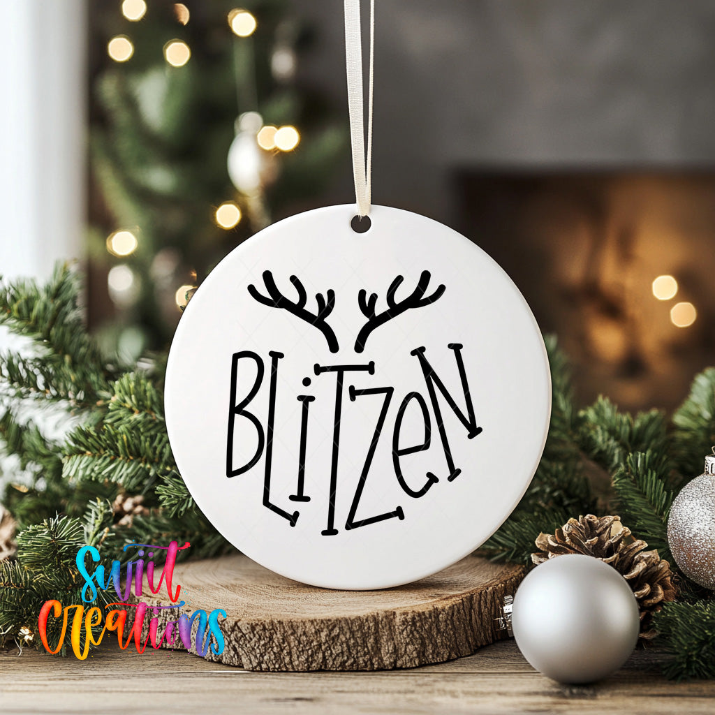 A white ornament with the word "Blitzen" written on it, hanging from a string, surrounded by Christmas decorations such as pine branches and ornaments.