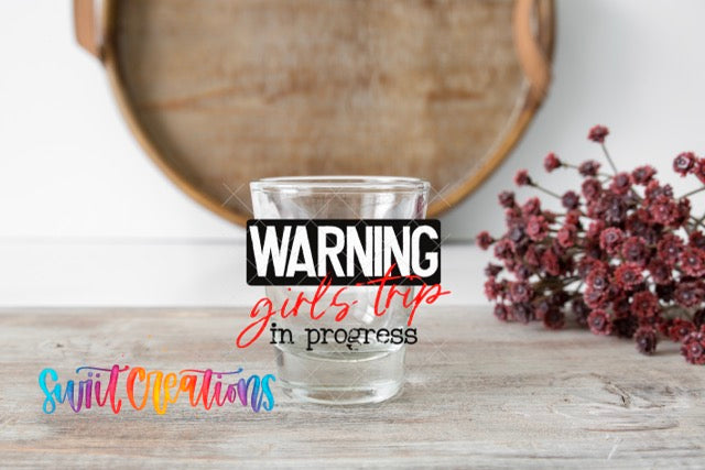 a glass with a warning sign on it, placed on a wooden surface. There is also a bouquet of flowers in the background.