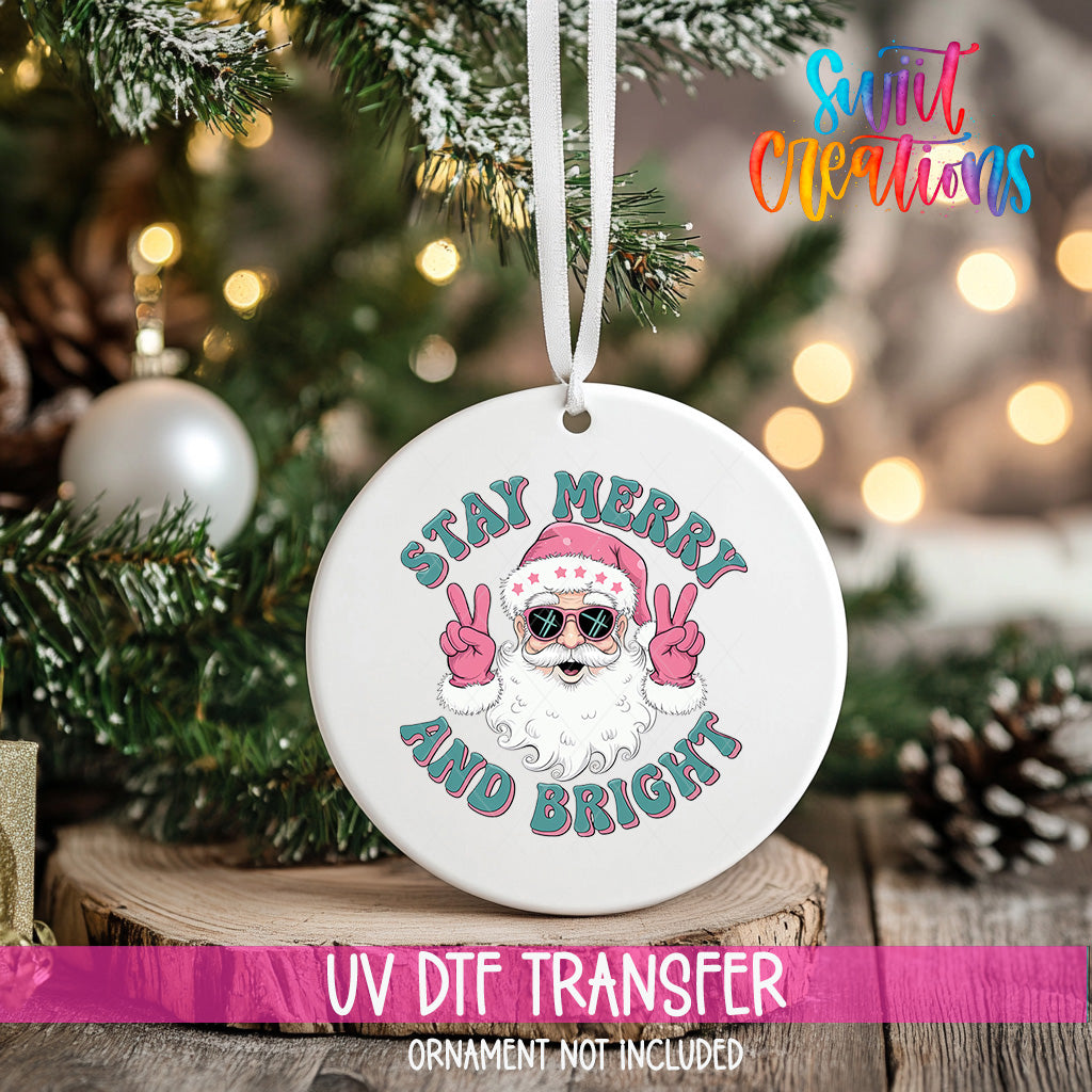 A white ornament with a Santa Claus design and the text "Stay Merry and Bright" hanging from a Christmas tree.