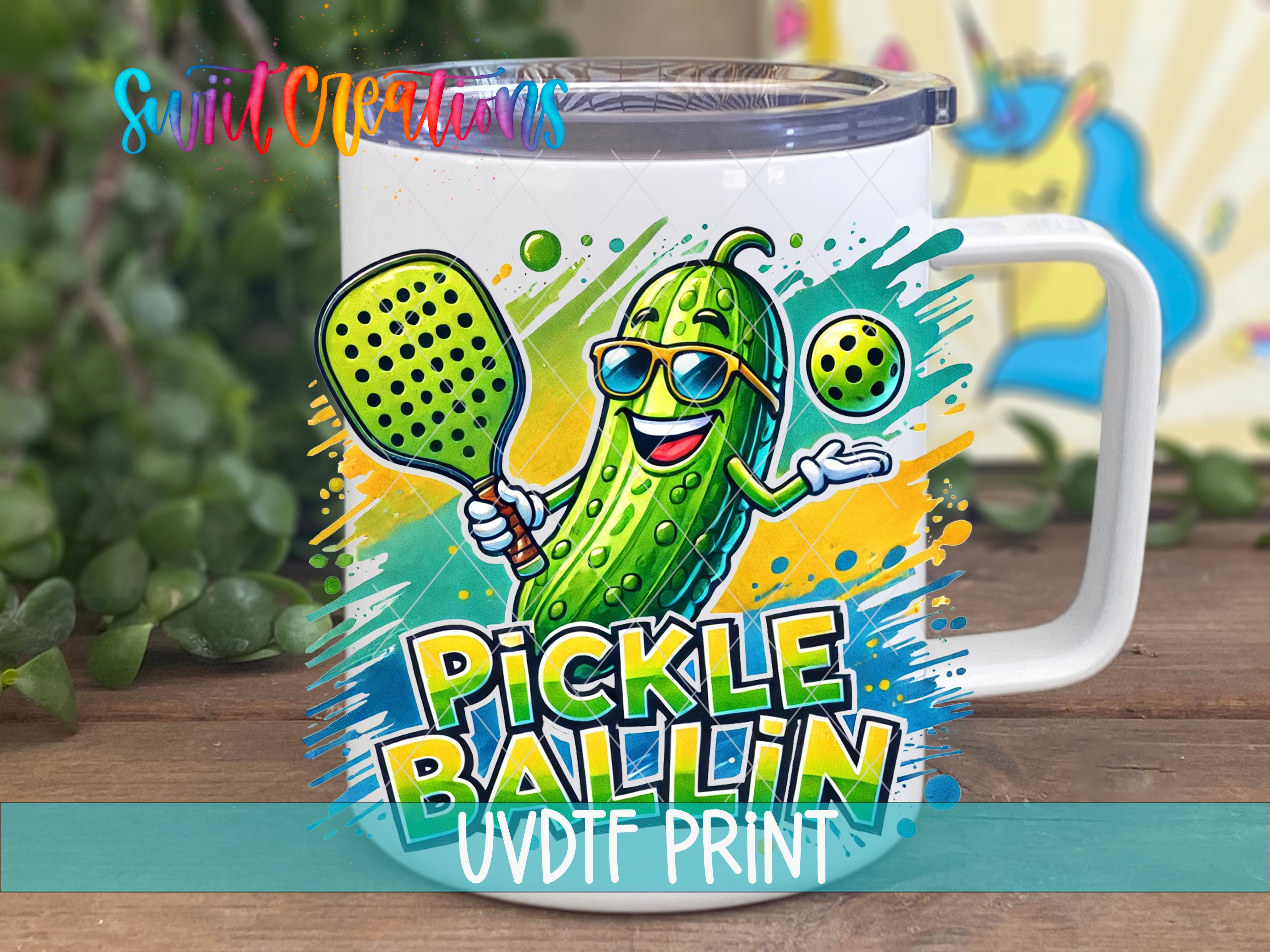 A mug with a cartoon image of a pickle wearing sunglasses and holding a tennis racket, with the text "Pickle Ballin" and "UVDF Print" printed on it.