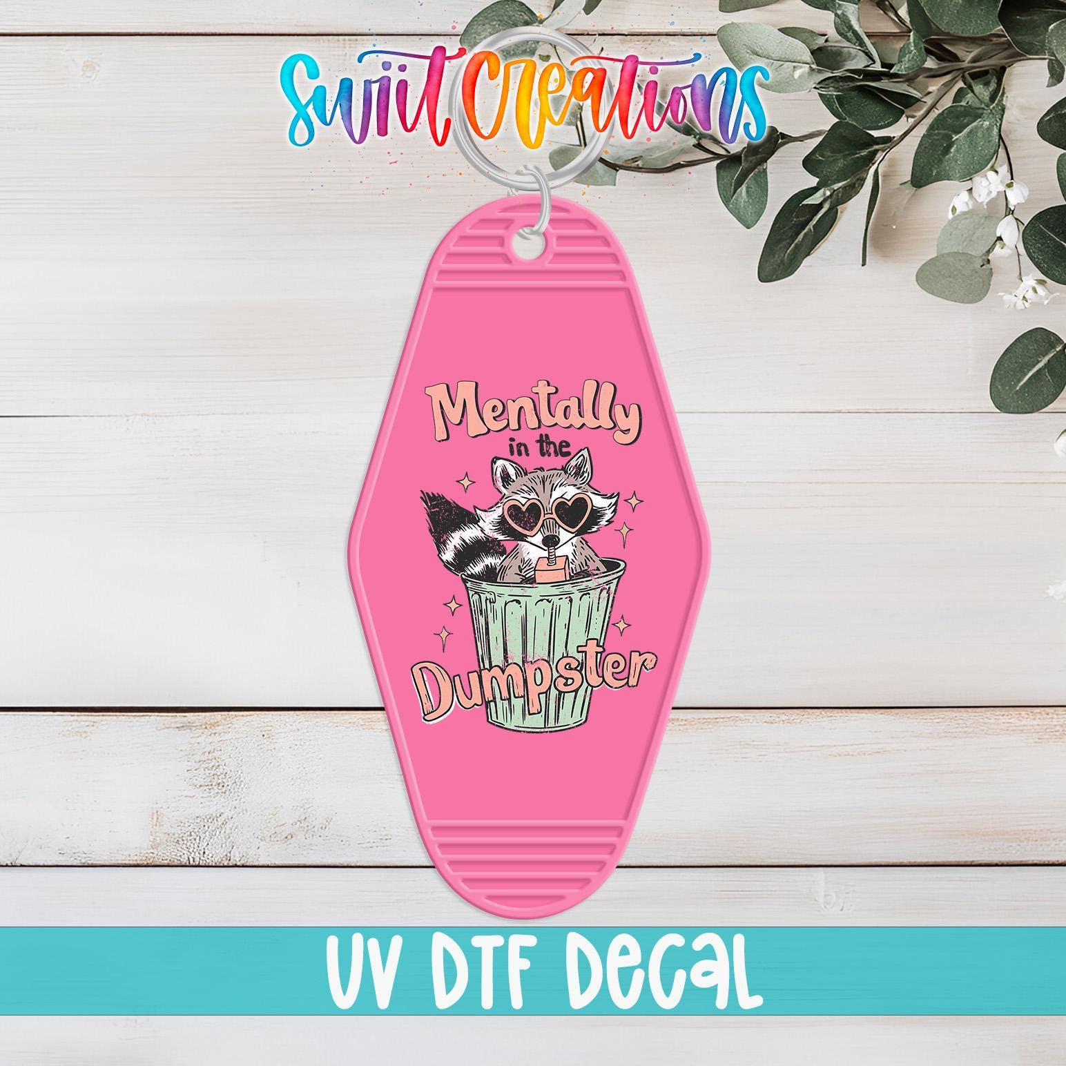 A pink keychain with a cartoon raccoon and the text "Mentally in the Dumpster" printed on it, along with the text "UV Dtf Decal" at the bottom.