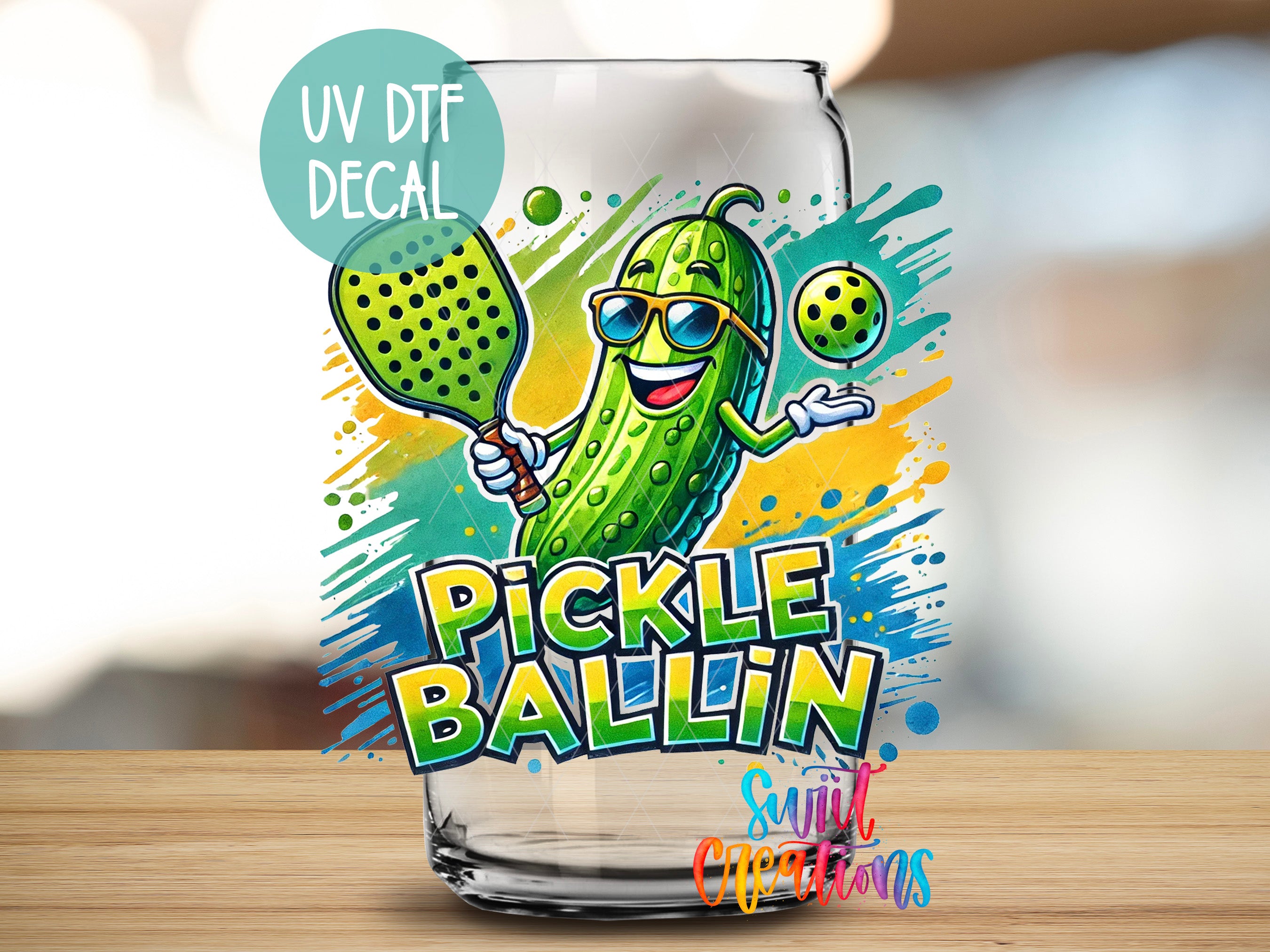A glass with a cartoon image of a pickle wearing sunglasses and holding a tennis racket, with the text "PICKLE BALLIN" and "UV DTF DECAL" printed on it.
