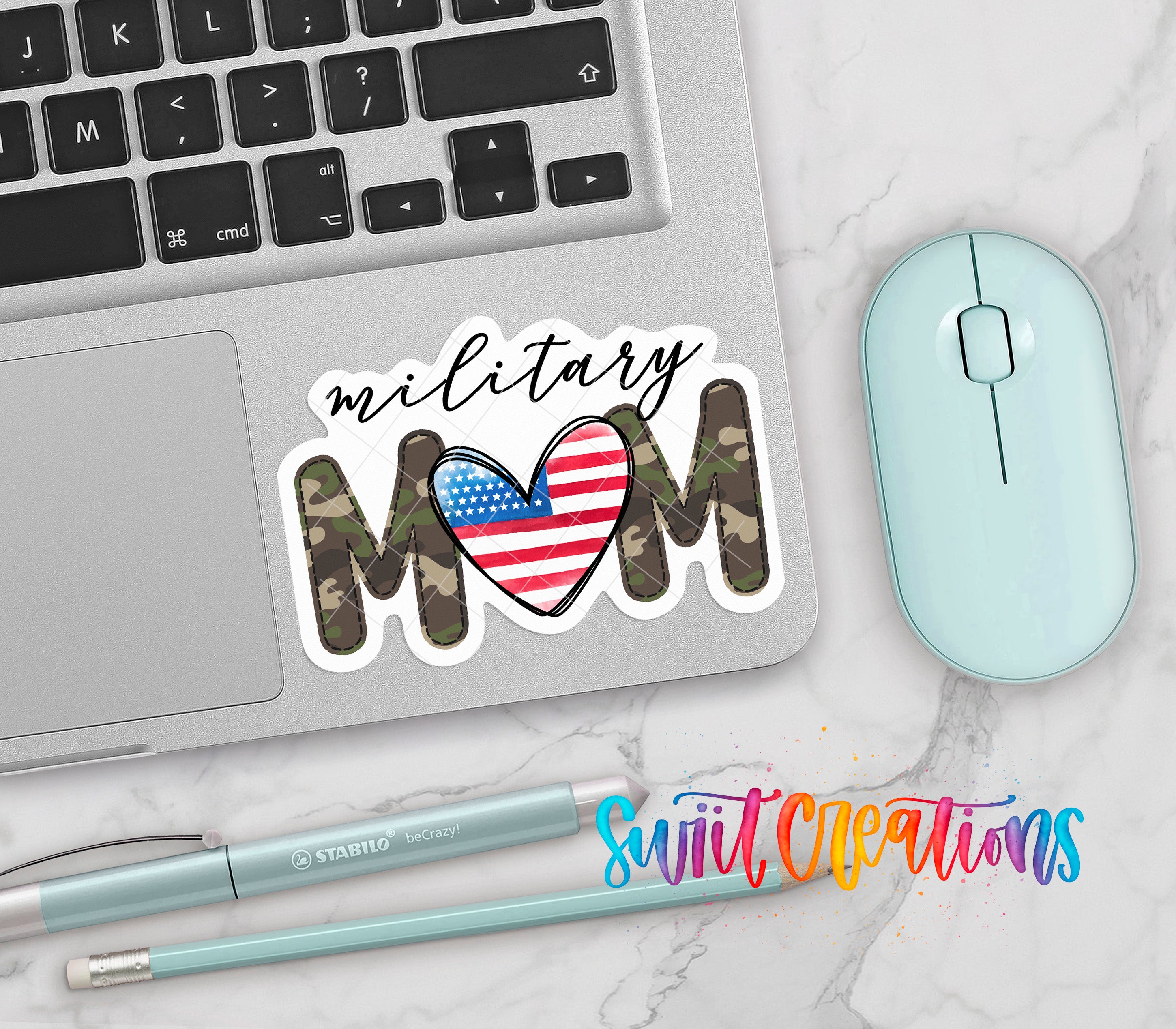a laptop with a sticker that says "Military Mom" and an American flag design, along with a mouse and a pen on a marble surface.