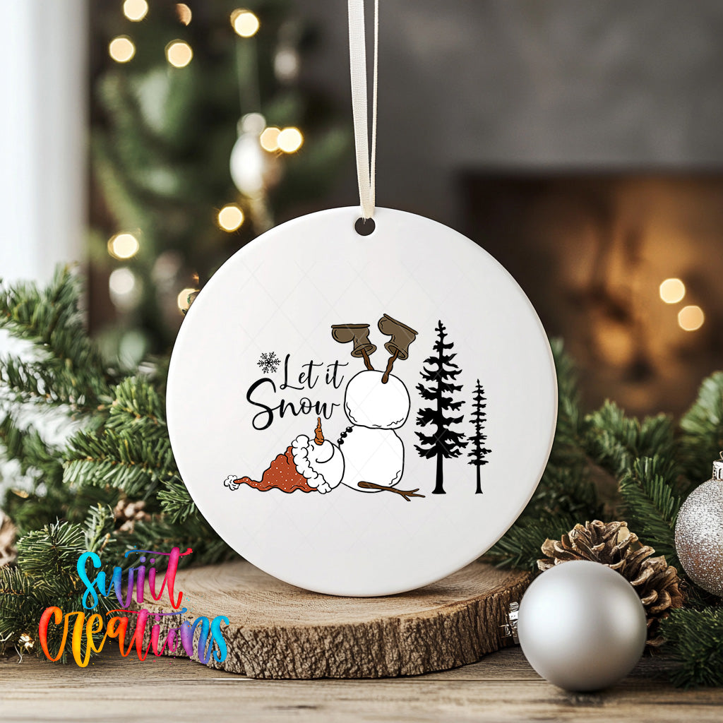 A white ceramic ornament with a snowman and Christmas trees, along with the text "Let it Snow" is displayed on a wooden surface, surrounded by Christmas decorations and ornaments.