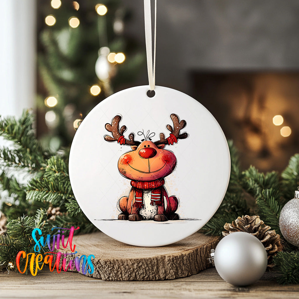 A white ceramic ornament featuring a cartoon reindeer with antlers, sitting on a wooden surface surrounded by Christmas decorations.