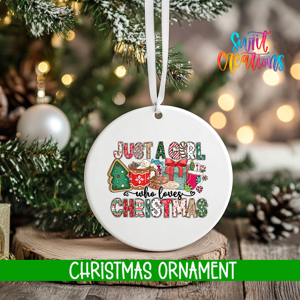 A white Christmas ornament with the text "JUST A GIRL WHO LOVES CHRISTMAS" printed on it, hanging from a tree branch.