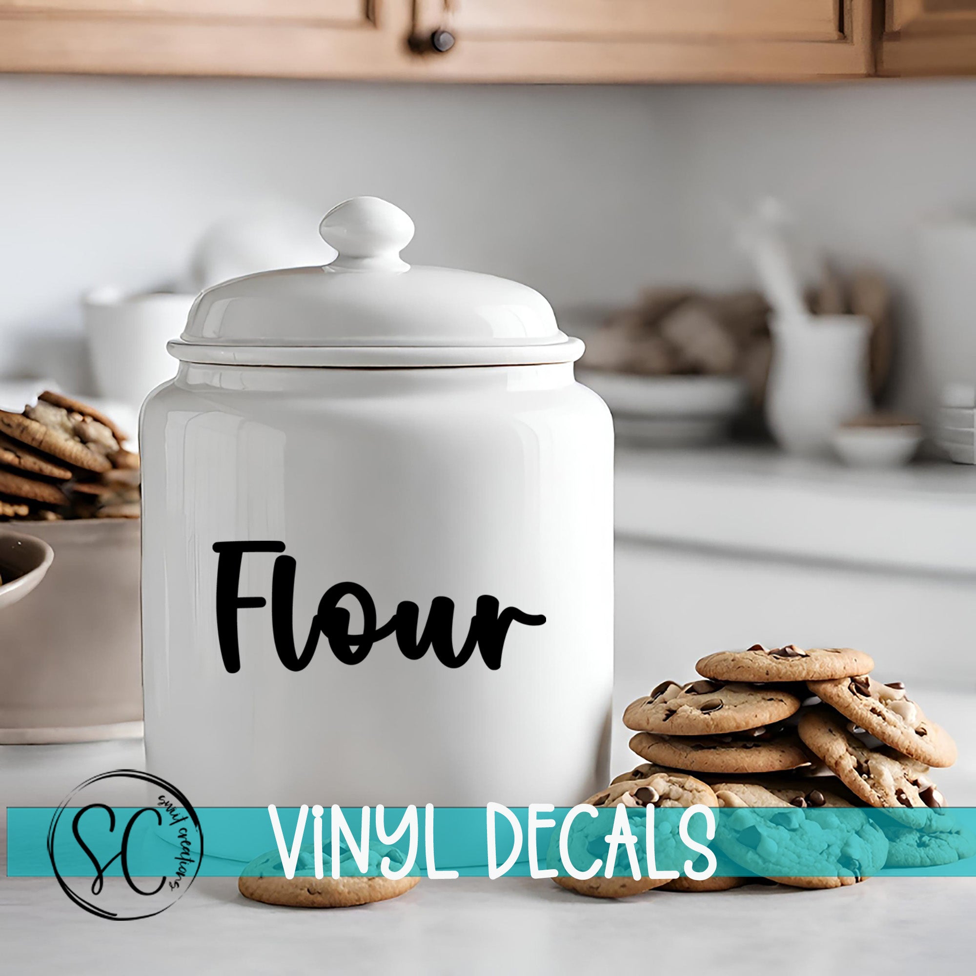 A white ceramic jar with the word "Flour" printed on it, placed on a kitchen counter next to a stack of chocolate chip cookies.