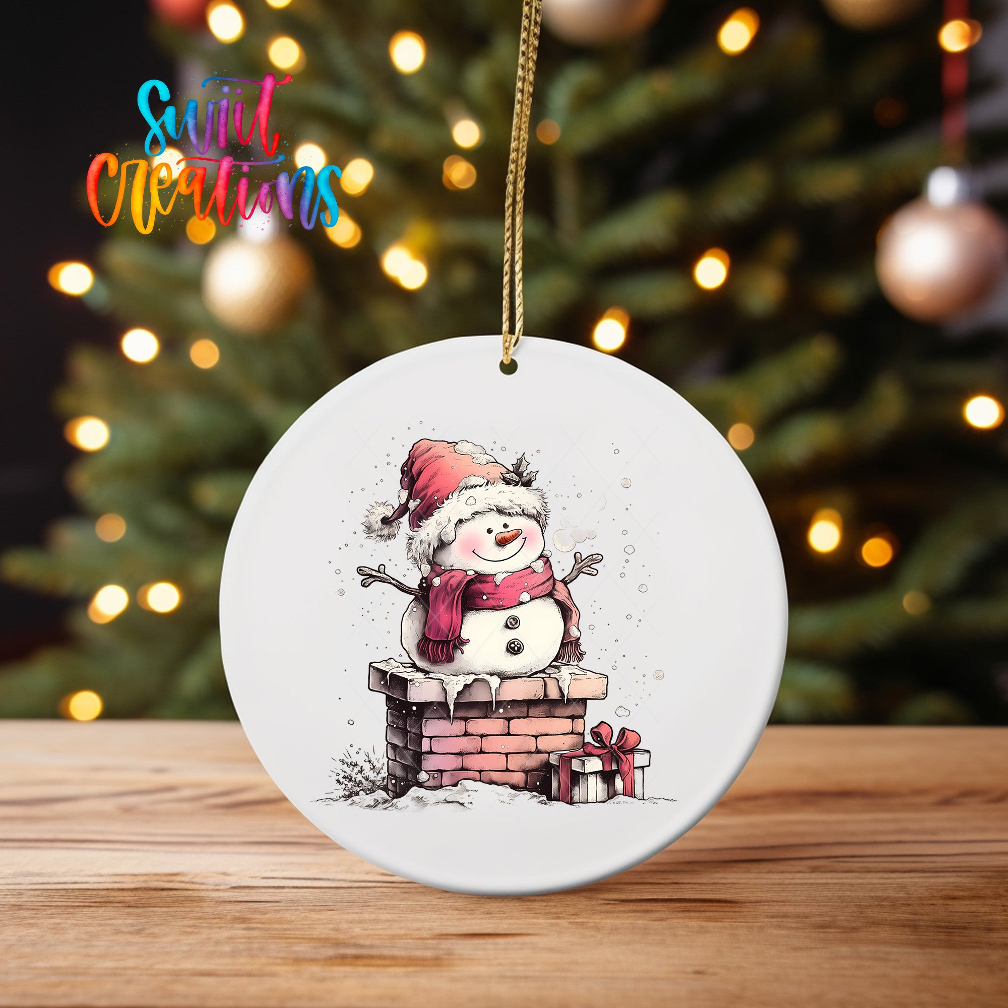 A white oval ornament featuring a snowman sitting on a brick chimney, with a Christmas tree and twinkling lights in the background.