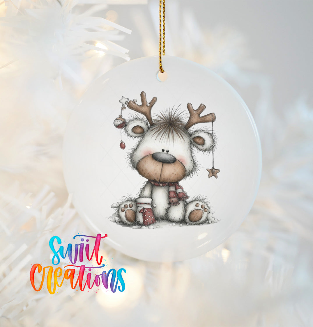 A white ornament with a cute reindeer design hanging on a Christmas tree.