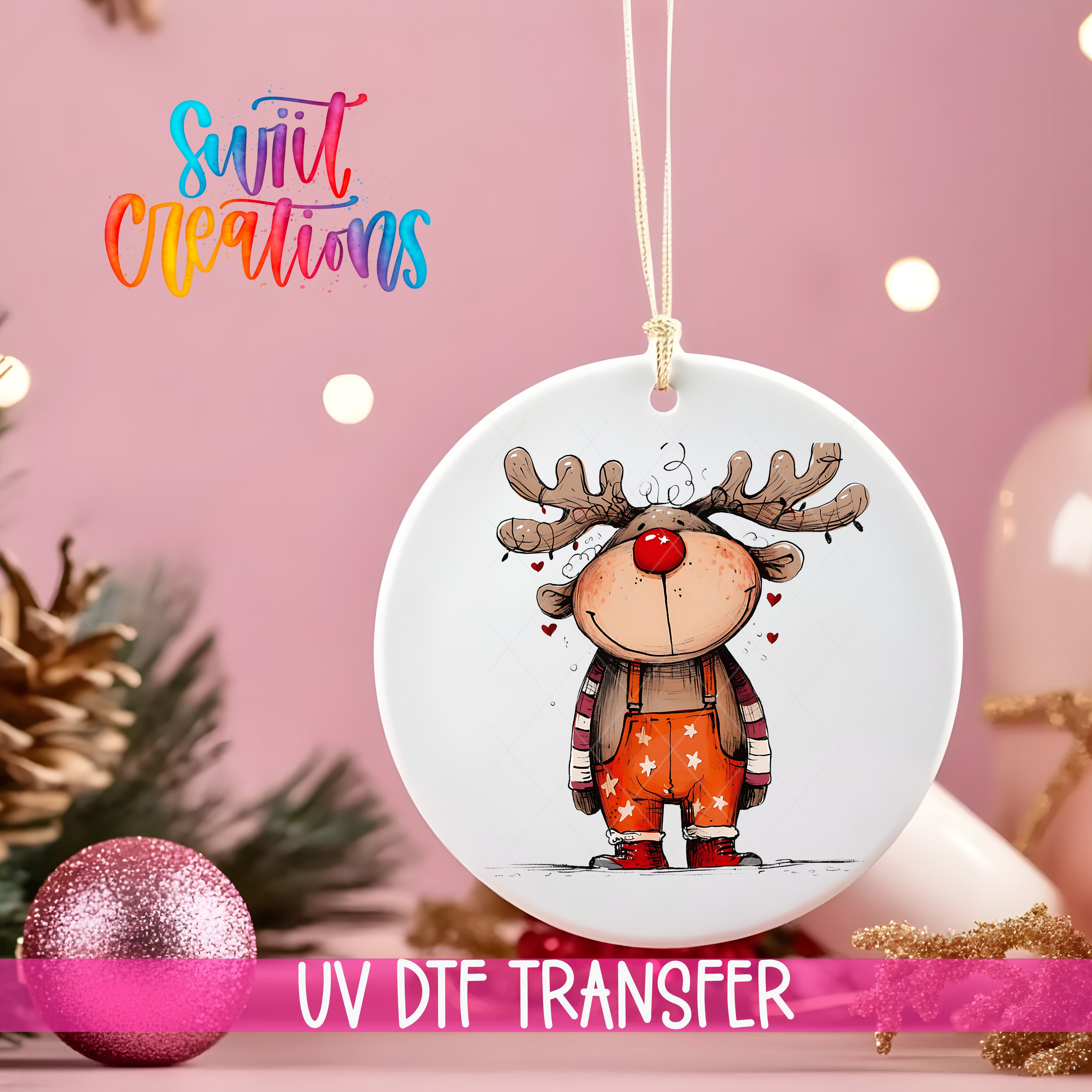A white ornament with a cartoon reindeer design hangs against a pink background, with a pink glitter ball and pine cones in the foreground.
