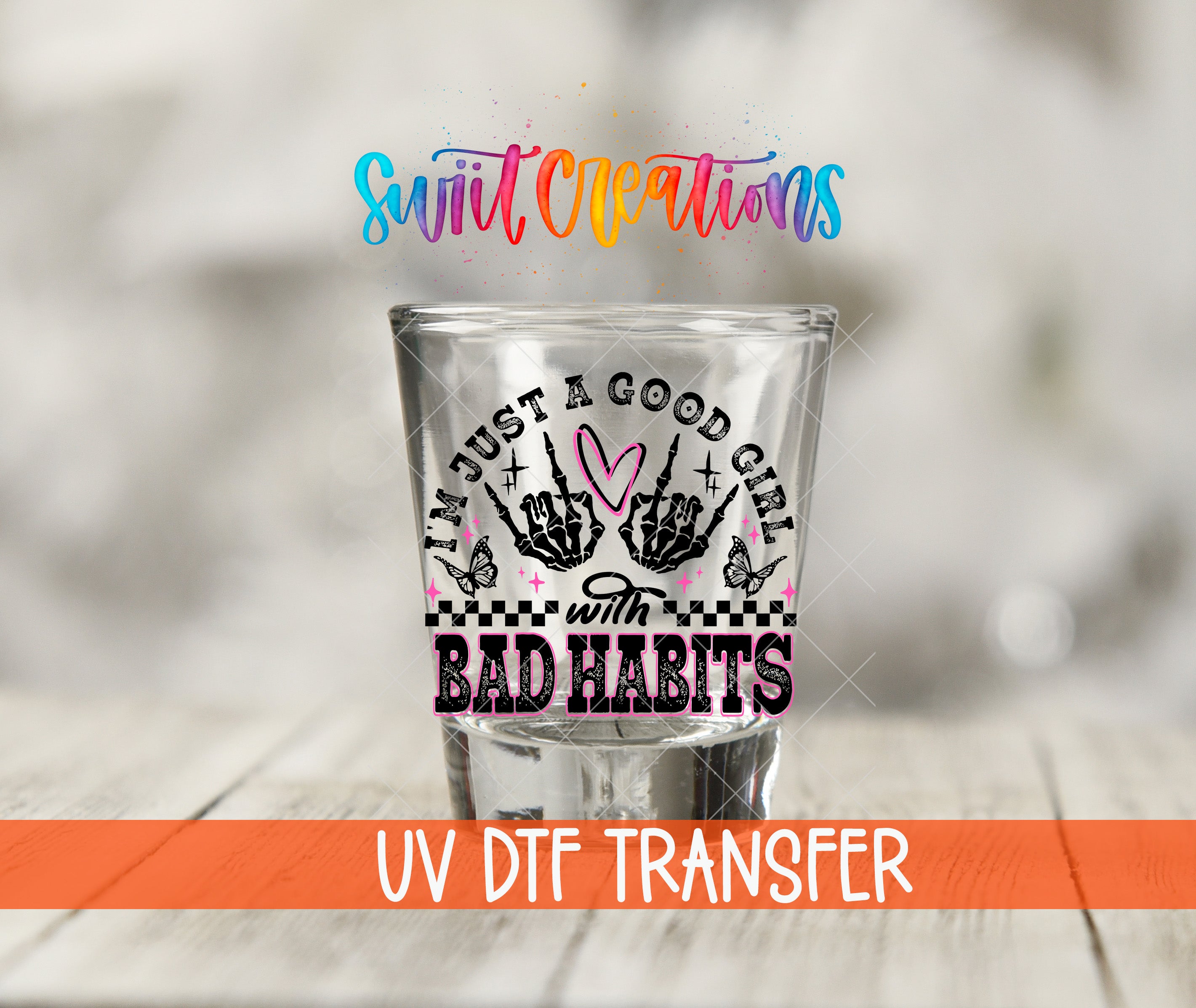 A shot glass with a colorful design and text, placed on a wooden surface.