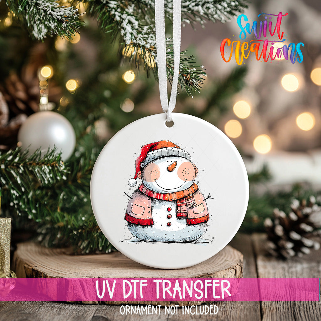 A white ceramic ornament featuring a snowman is hanging on a Christmas tree, with a blurred background of pine branches and twinkling lights.