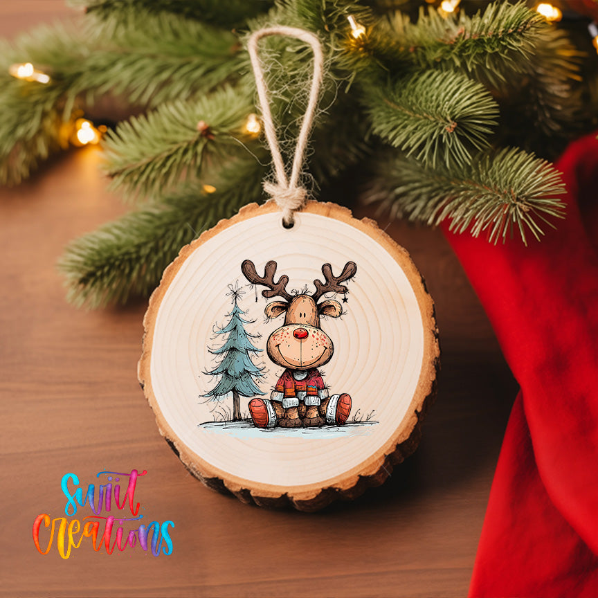 A wooden ornament featuring a cartoon reindeer is hanging on a Christmas tree, surrounded by pine branches and twinkling lights.
