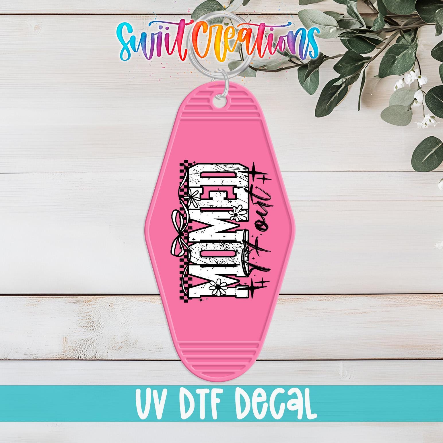 A pink keychain with the text "WONDER" printed on it, hanging on a wooden surface with some greenery in the background.