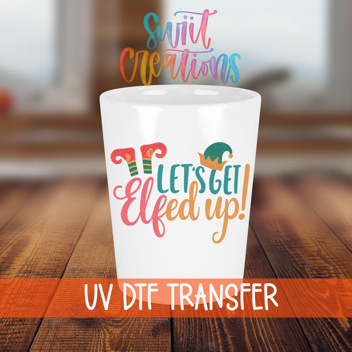 Let's Get Elfed Up shot glass transfer on a white shot glass on a wooden table
