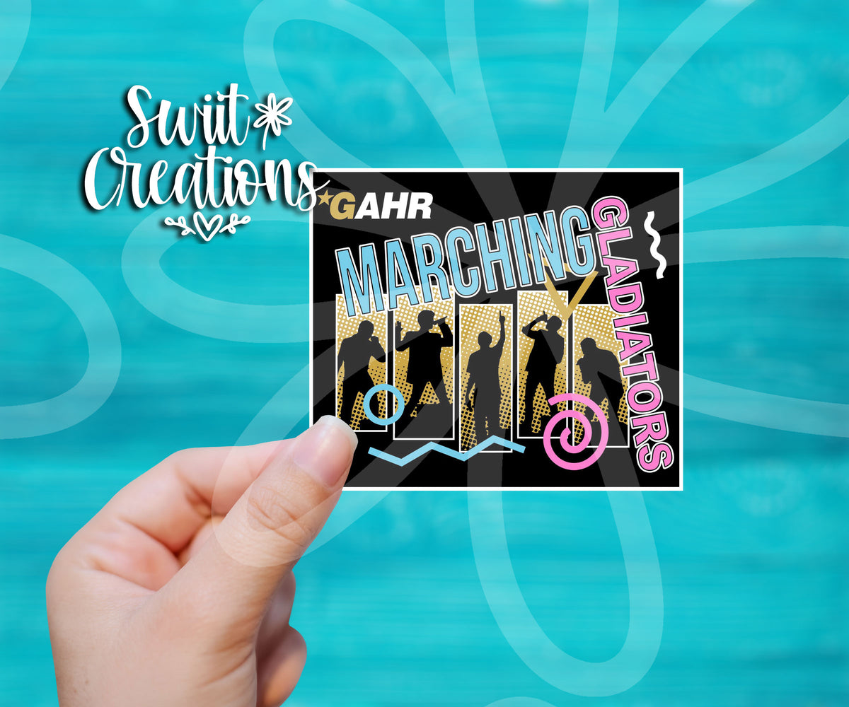 Hand holding a Gahr High Marching Gladiators 2022 sticker with band silhouettes on a gold background