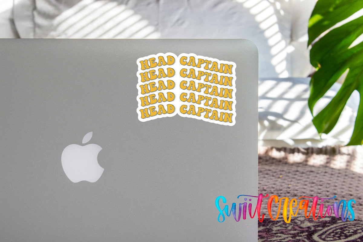 a sticker with the phrase "HEAD CAPTAIN" written in a playful font, placed on the back of a silver Apple laptop.