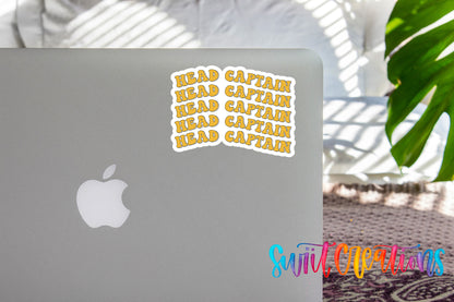 a sticker with the phrase "HEAD CAPTAIN" written in a playful font, placed on the back of a silver Apple laptop.