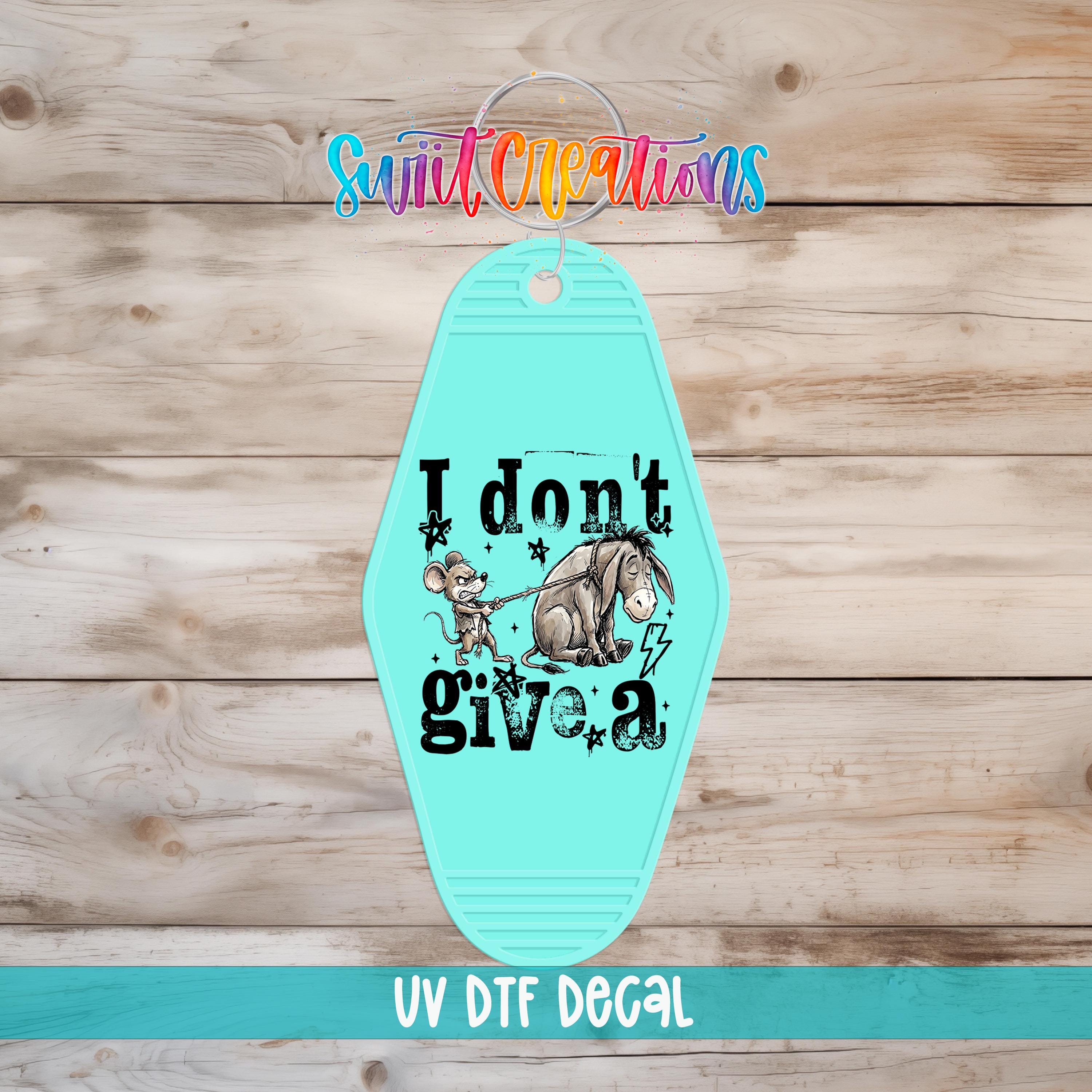 A turquoise keychain with a cartoon image of Eeyore and the text "I don't give a" printed on it.