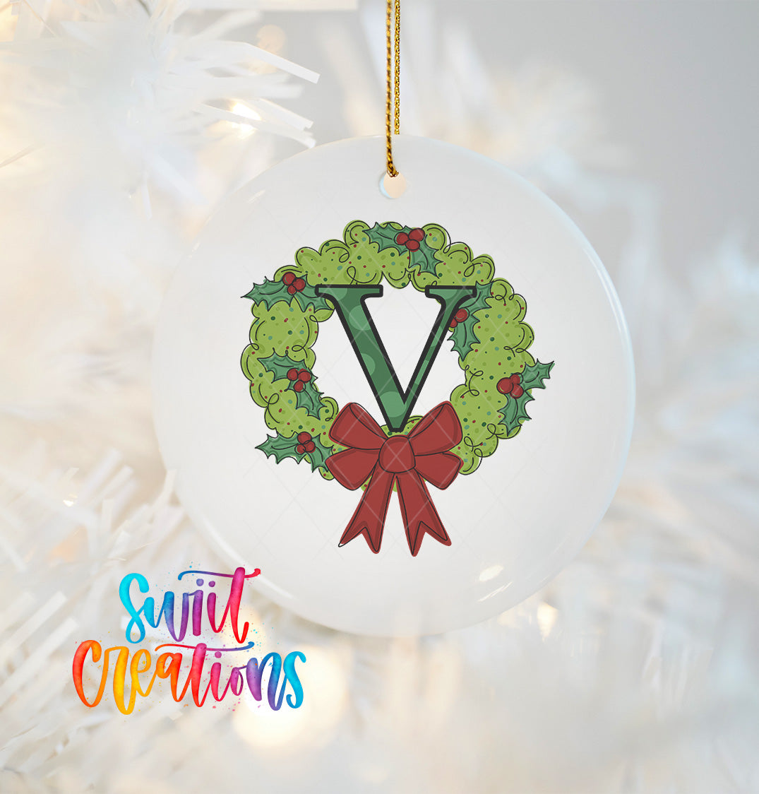 A white ornament with a green wreath and a red ribbon, featuring the letter 'V' in the center.